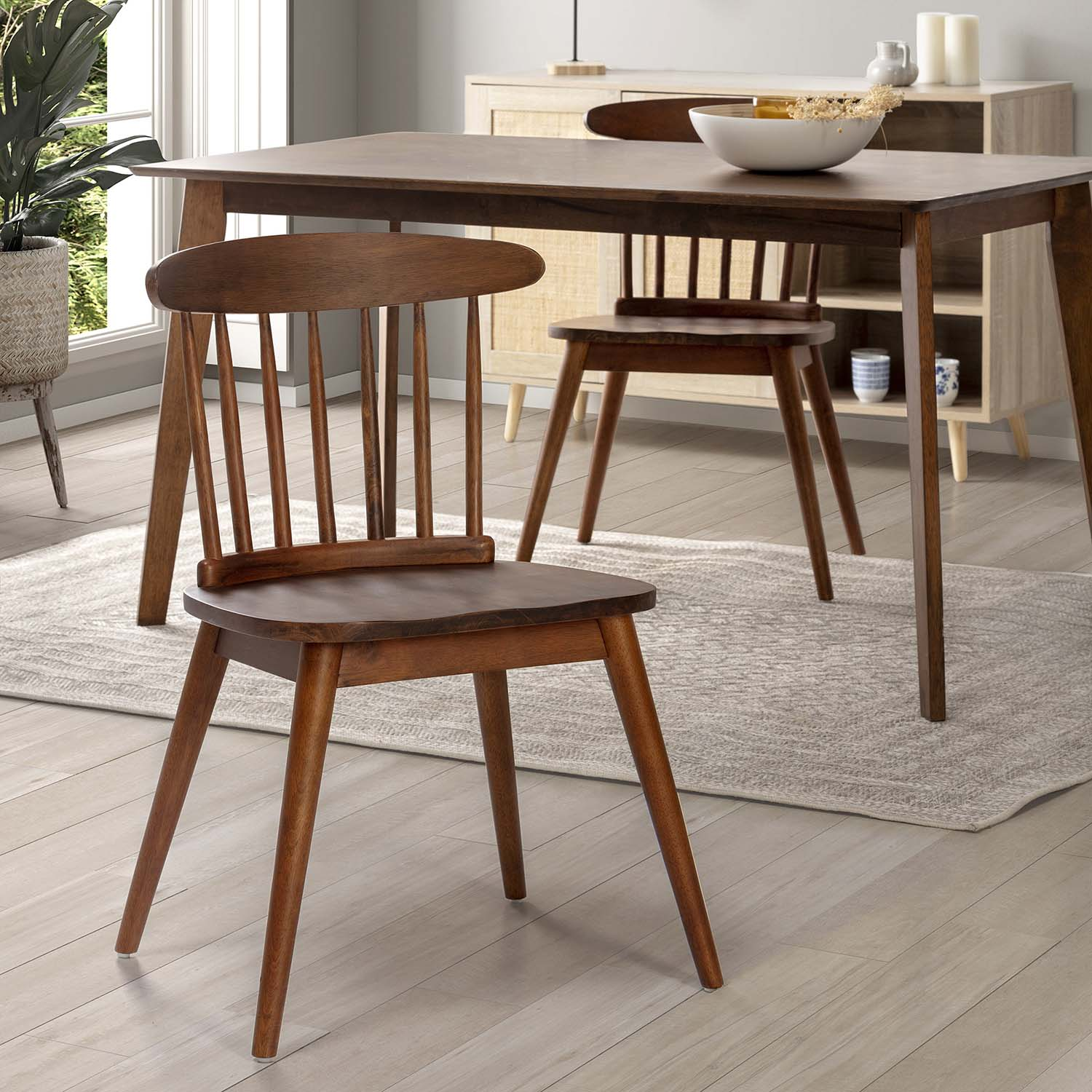 Una mesa de comedor de madera con cuatro sillas en una habitación luminosa con alfombra.