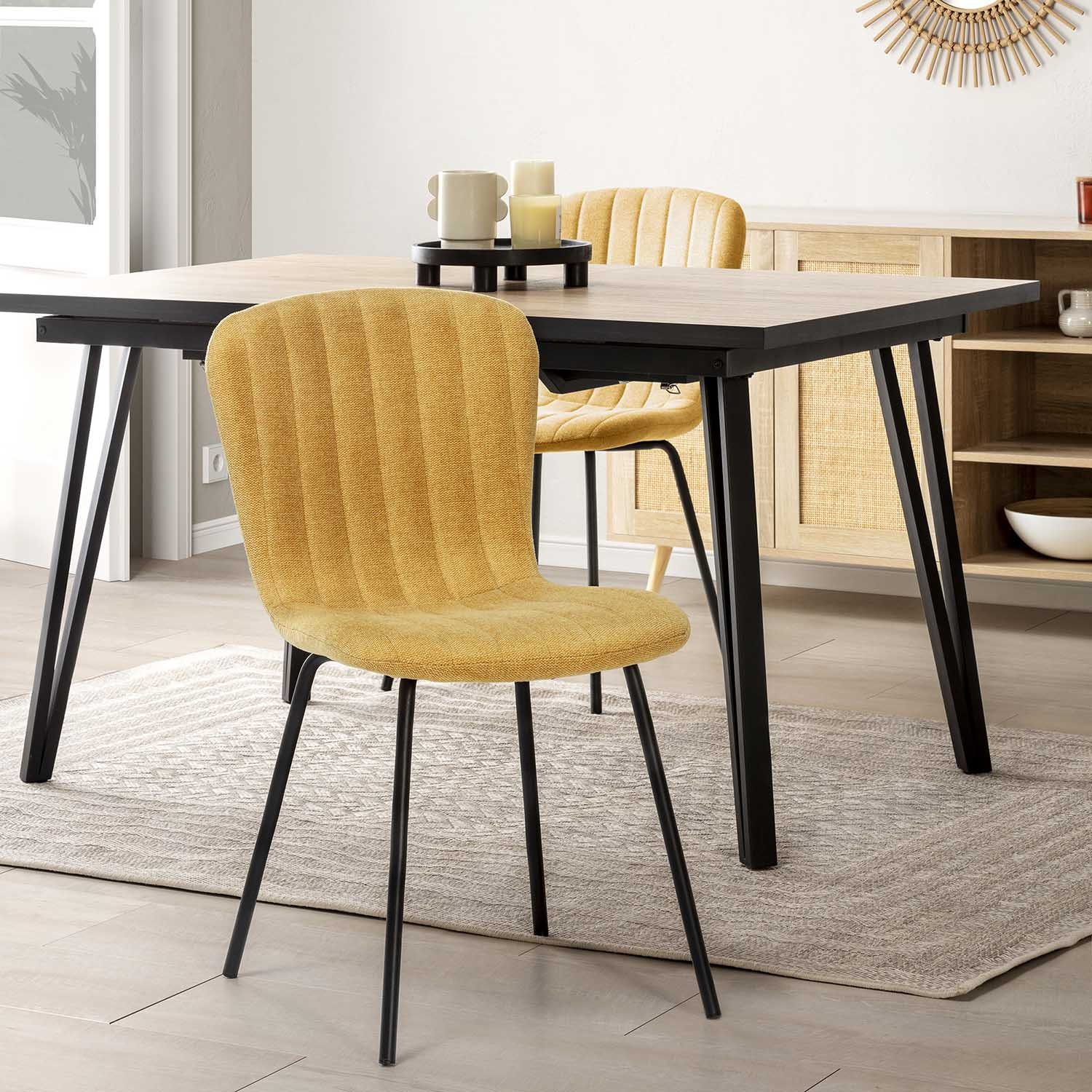 Silla de comedor amarilla con patas negras sobre alfombra junto a mesa de madera.