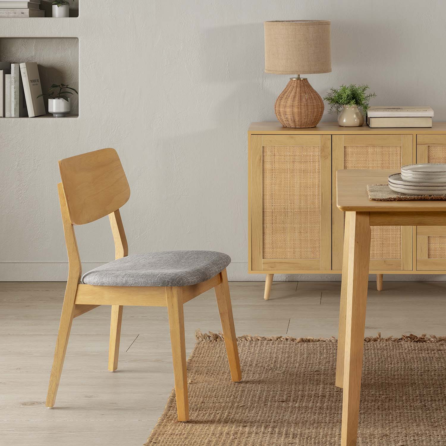 Una silla de madera con cojín gris delante de un aparador con puertas de ratán y pantalla.