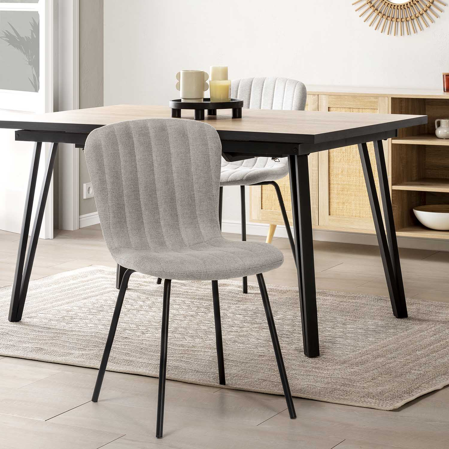 Silla de tela gris con patas negras sobre alfombra junto a mesa de comedor.