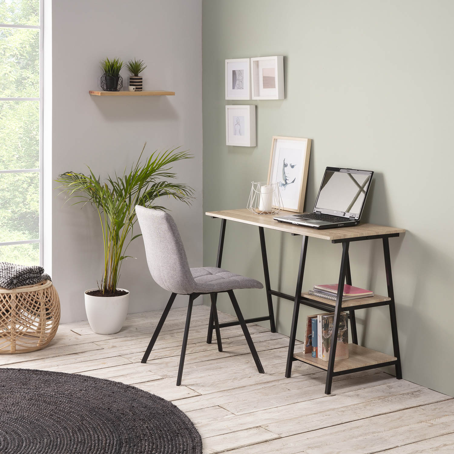 Un escritorio con portátil y plantas en una habitación luminosa con suelo de madera.