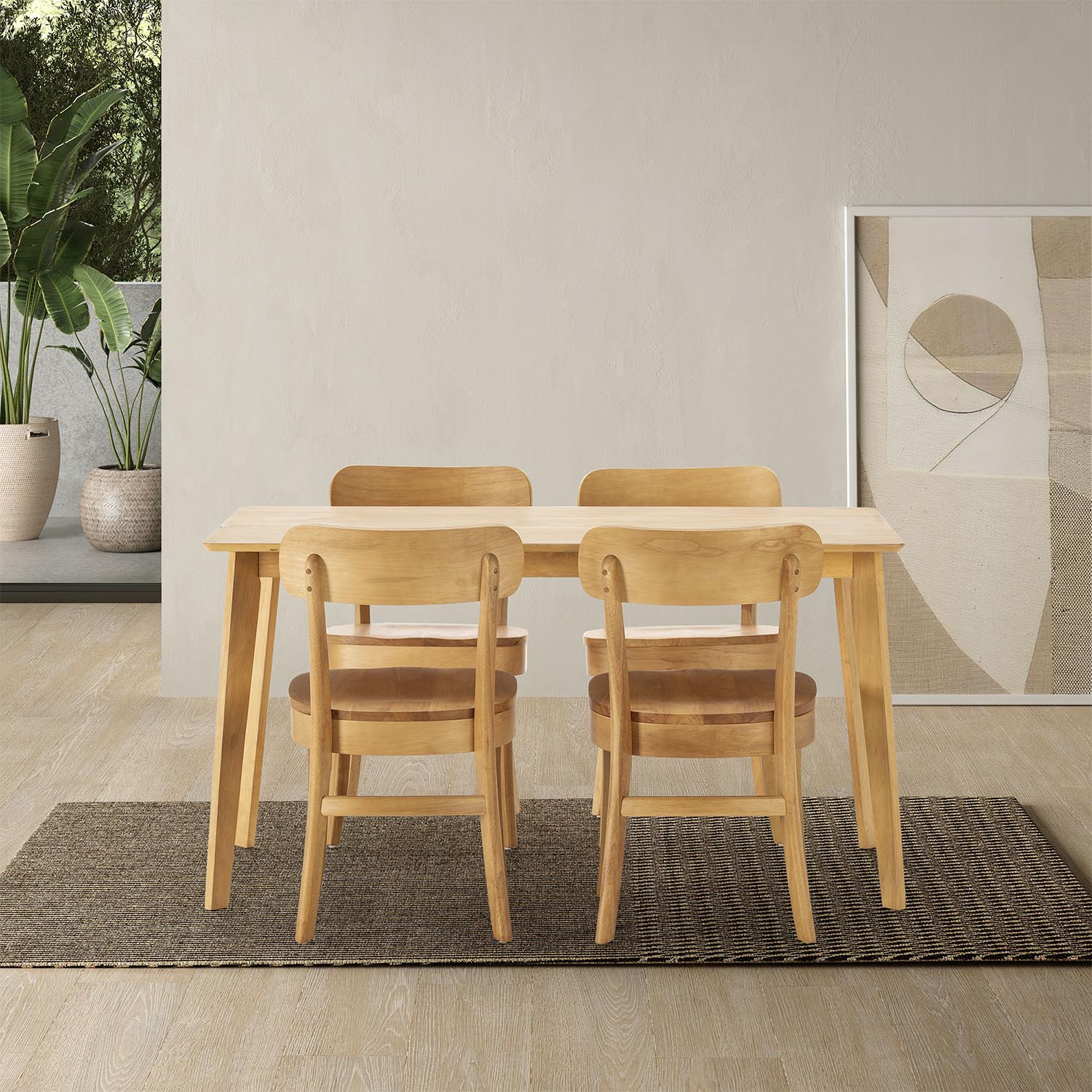 Una mesa de madera con cuatro sillas se asienta sobre una alfombra frente a una pared con un cuadro.