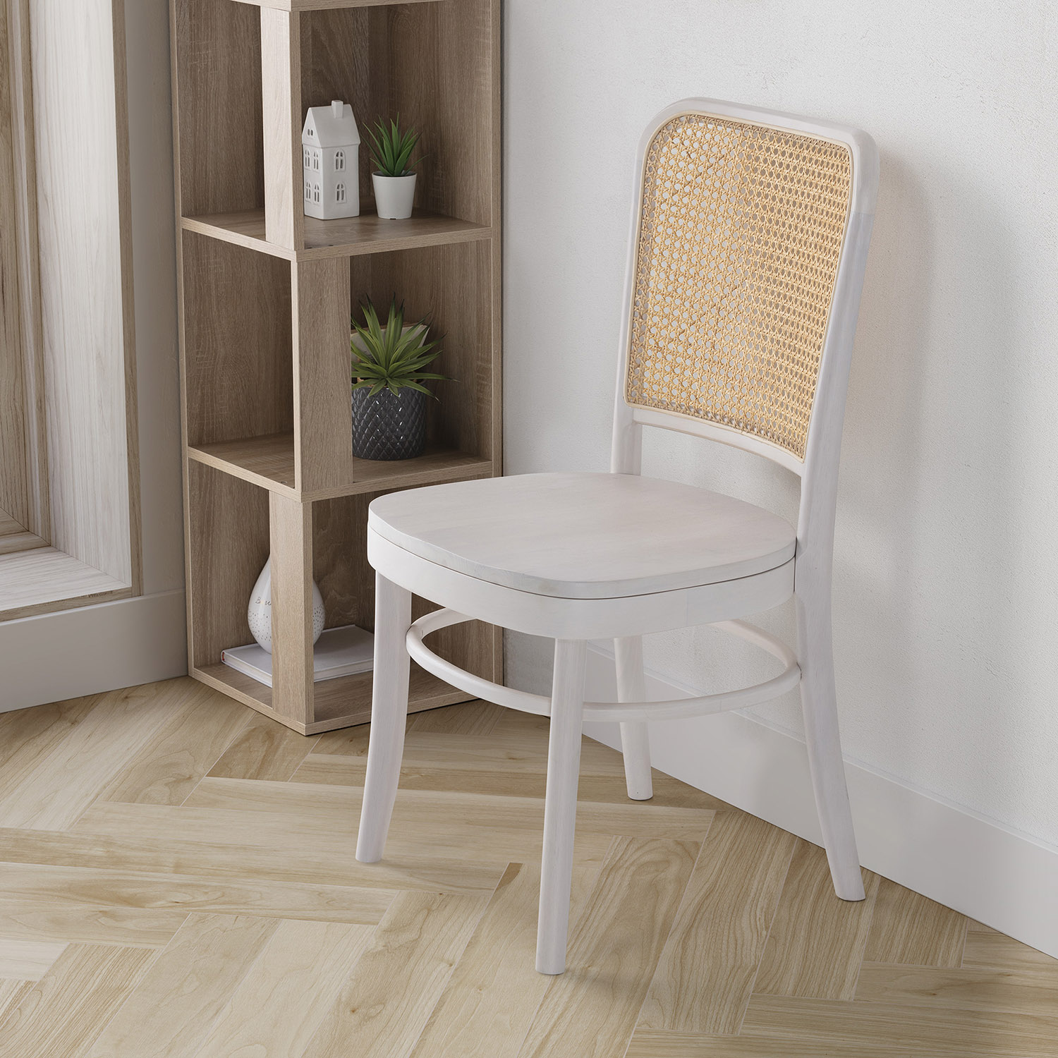 Una silla blanca con respaldo de ratán se encuentra junto a una estantería de madera.