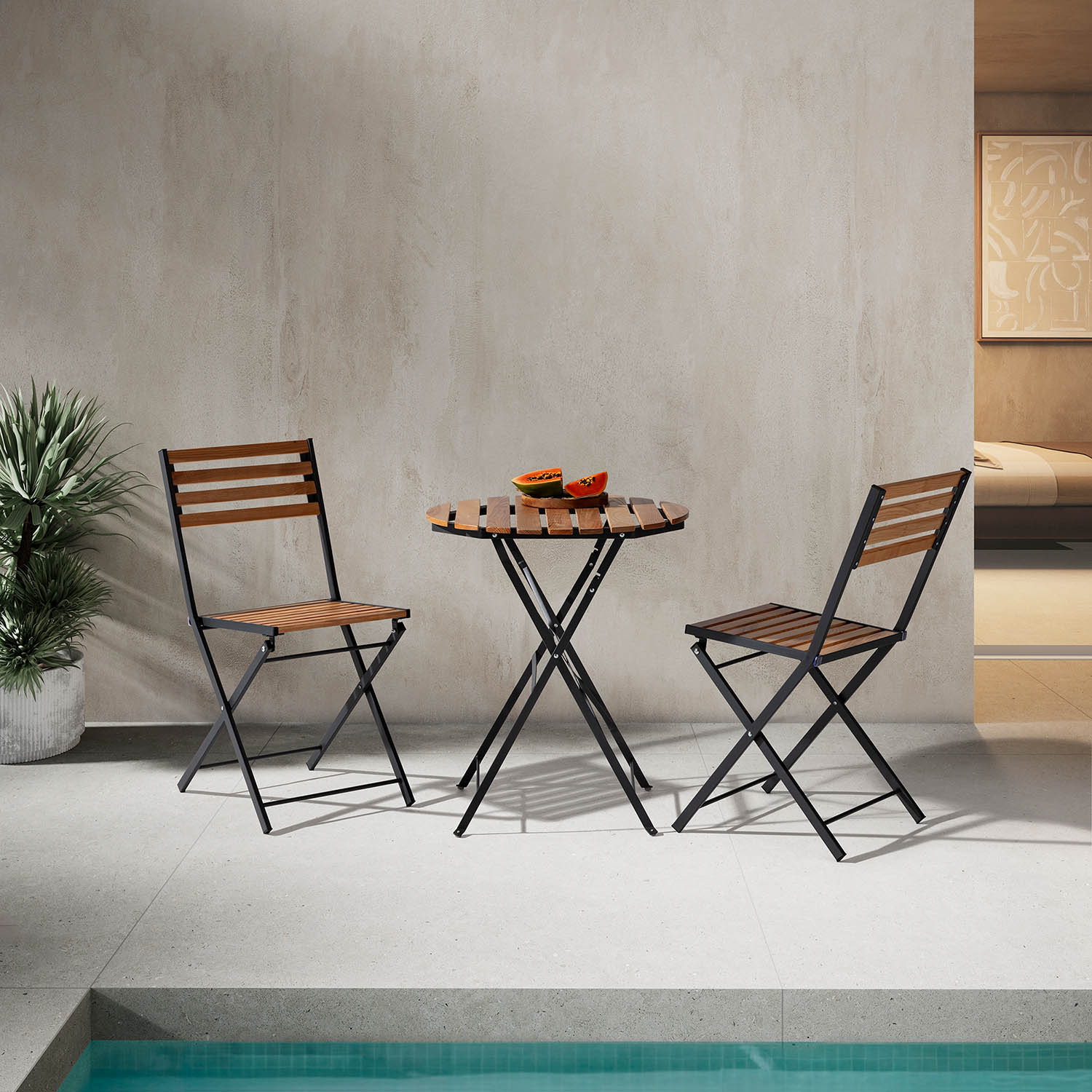 Una mesa redonda de madera con dos sillas se encuentra al aire libre junto a una piscina.