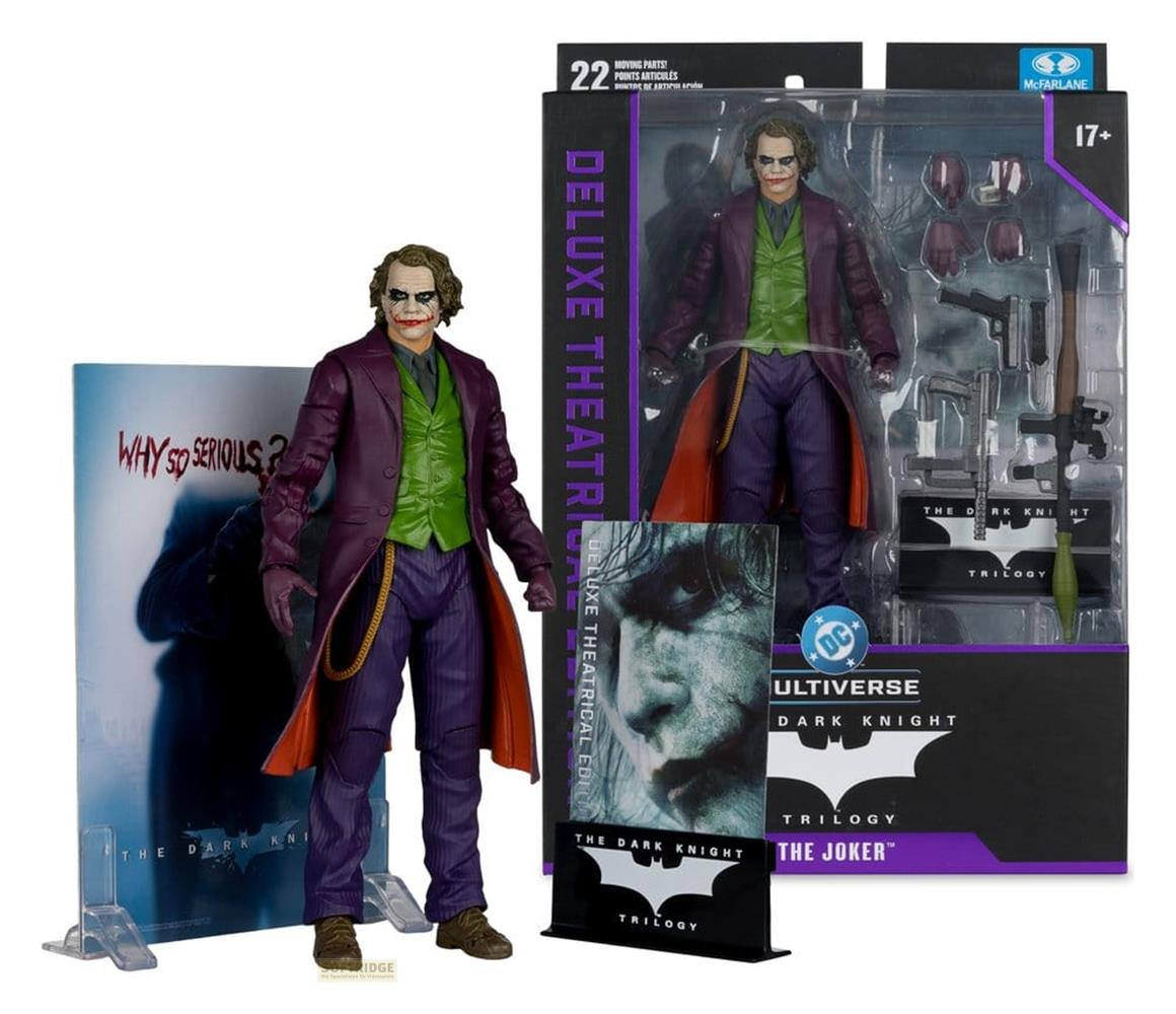 Joker-Actionfigur in Lila mit grüner Weste, neben Verpackung und "Why So Serious?"-Display.
