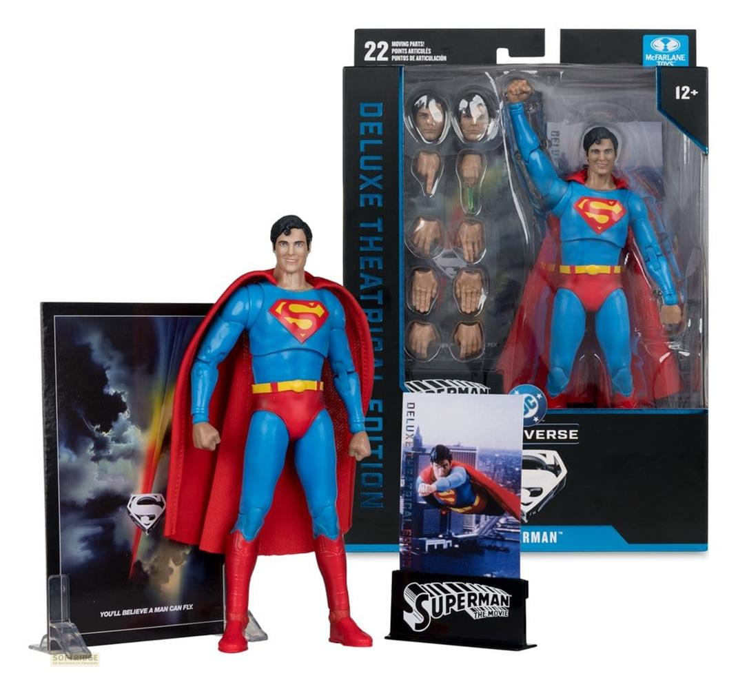 Superman-Actionfigur in Blauer und Roter Kleidung, mit Umhang. Zubehör und Verpackung sichtbar.