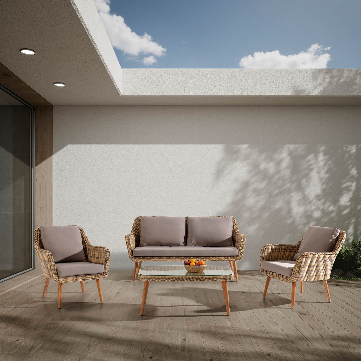 Mobiliario de exterior de mimbre con cojines y mesa de cristal en terraza de madera.