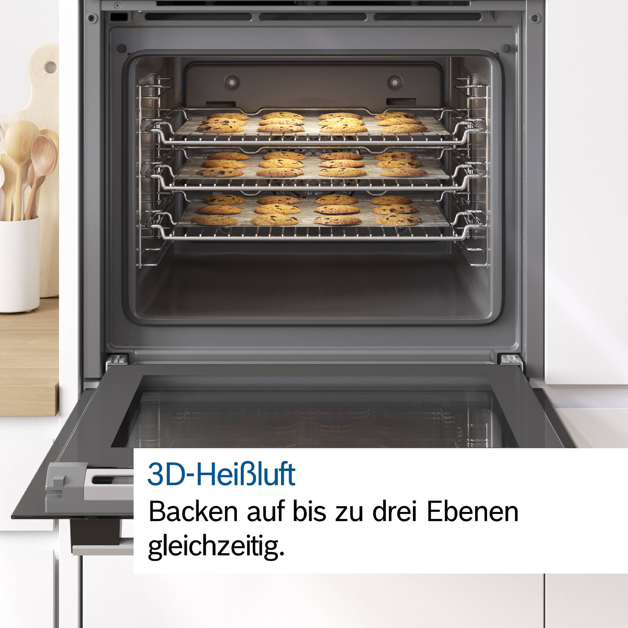 Offene Backröhre mit drei Gitterrosten voller Chocolate Chip Cookies.