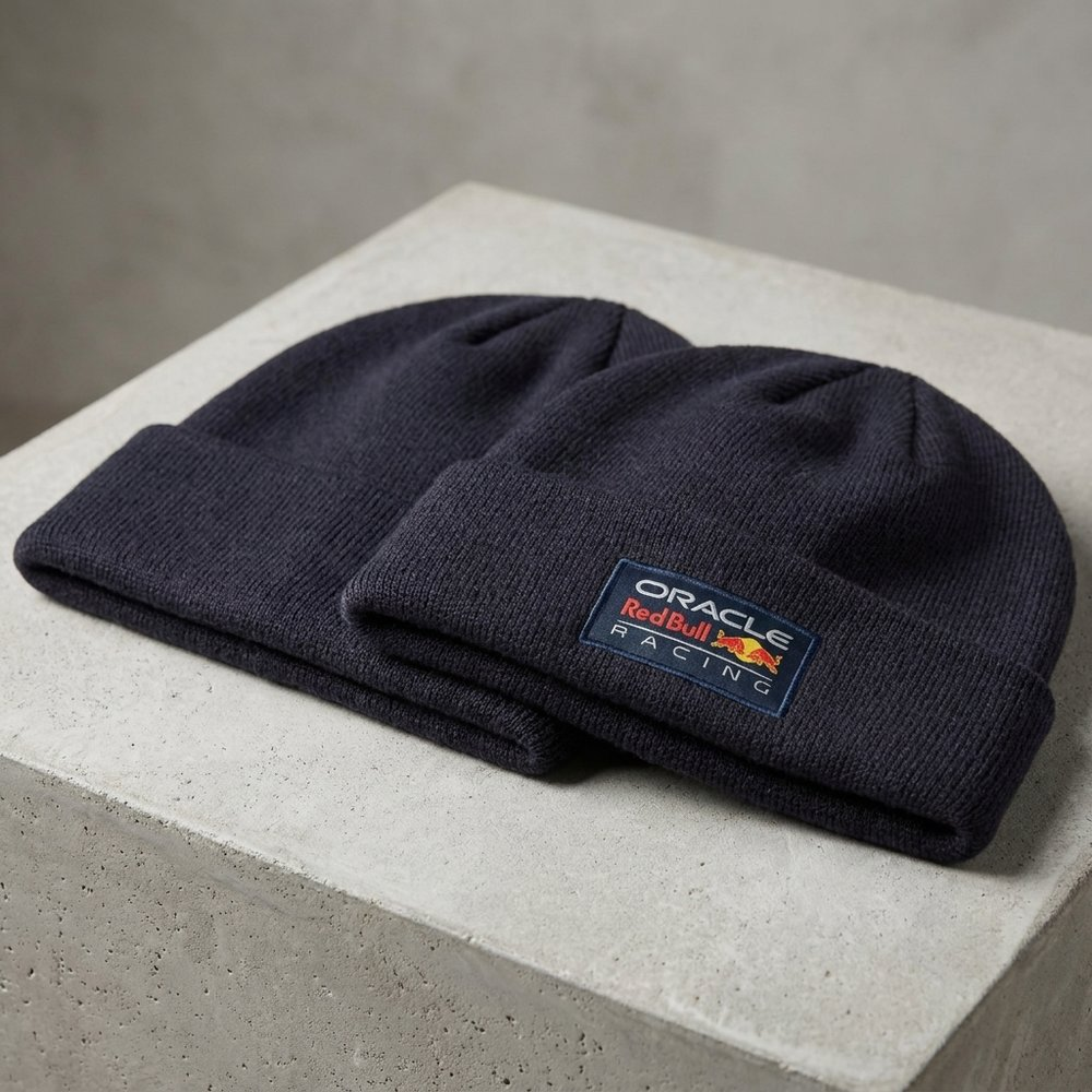 Due berretti blu scuro con logo Oracle Red Bull Racing su superficie di cemento.