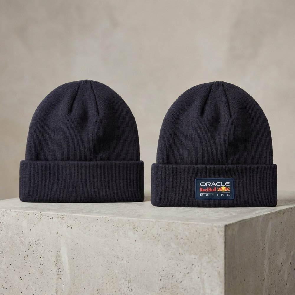 Due berretti blu scuro con logo Oracle Red Bull Racing su superficie di cemento.