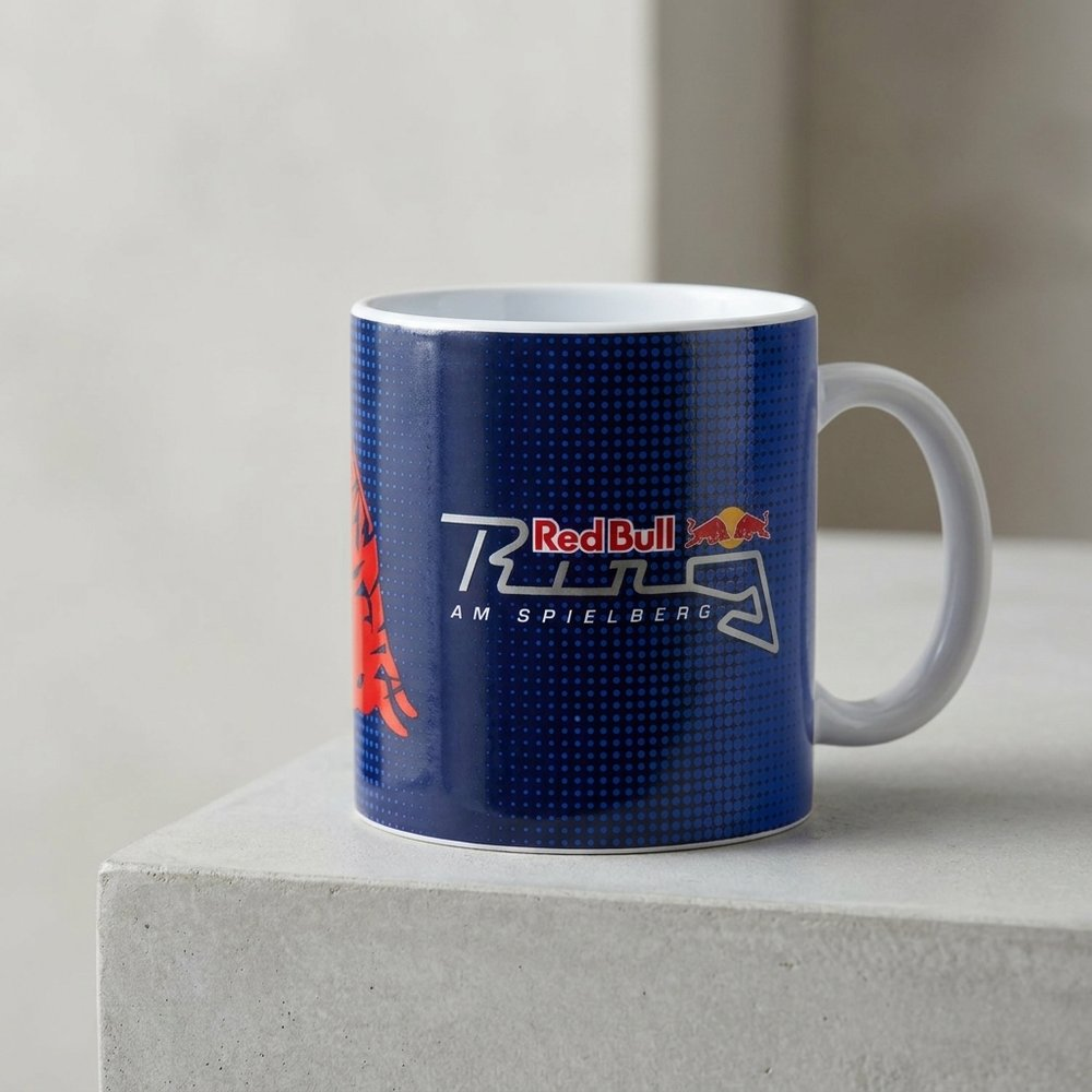 Tazza blu con logo Red Bull e grafica di pista, su superficie di cemento.