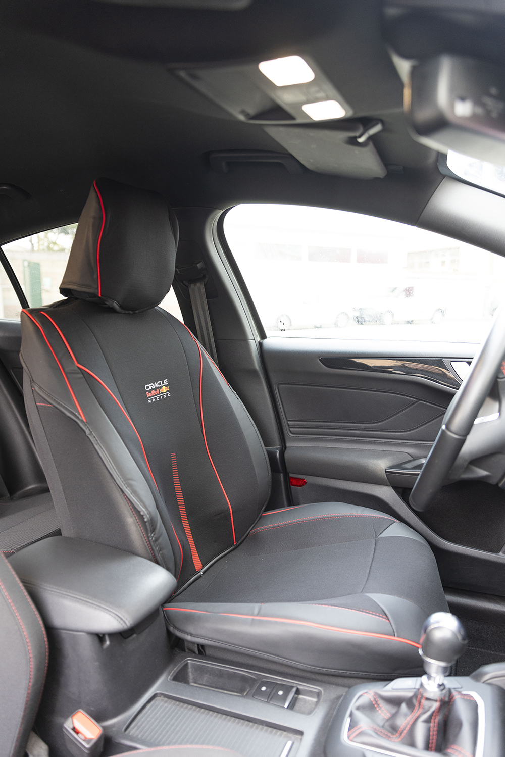 Coprisedile auto nero con cuciture rosse e logo Red Bull Racing.