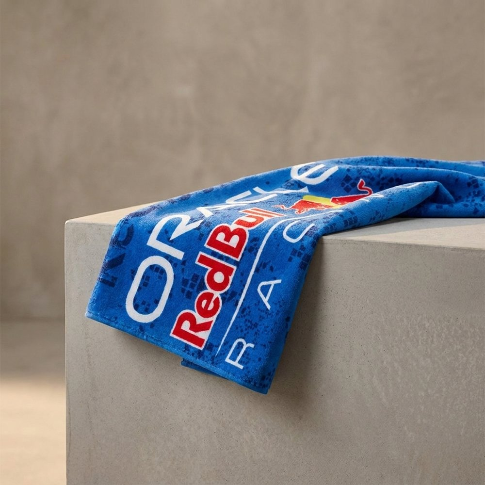 Un asciugamano blu con il logo Red Bull Racing poggia su una superficie di cemento.