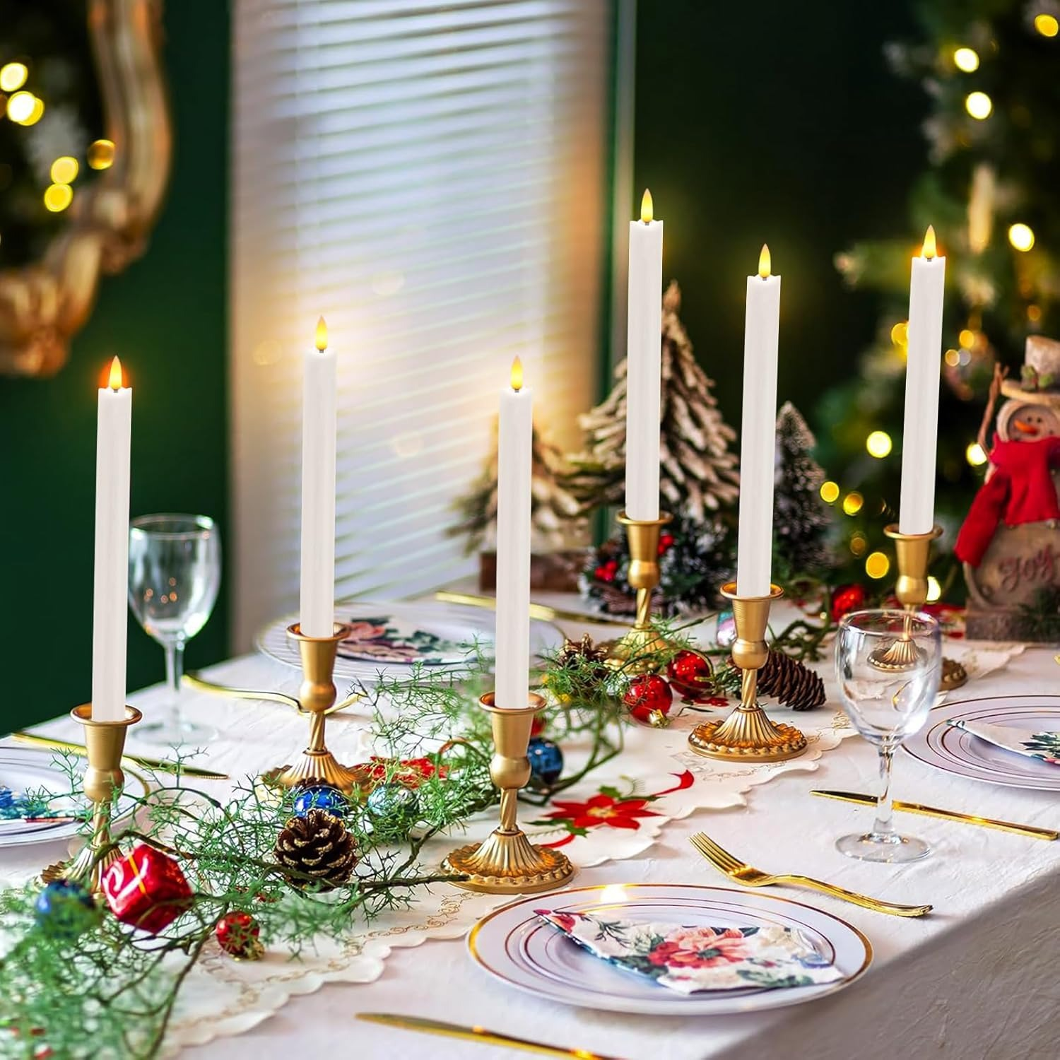 Ein Tisch für Weihnachten gedeckt mit weißen Kerzen, Tannengirlande, Schmuck und Tellern.
