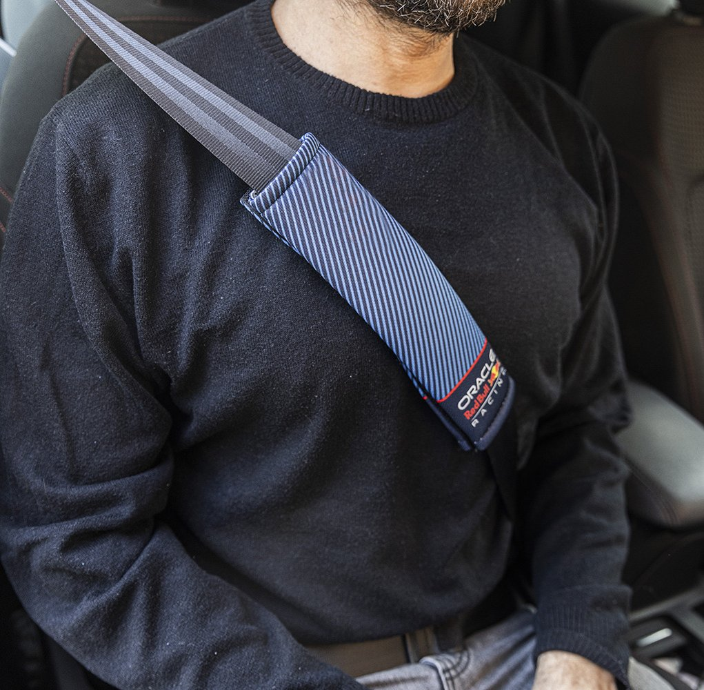 Un uomo con maglione nero indossa un copricintura blu con logo "Oracle Red Bull Racing".