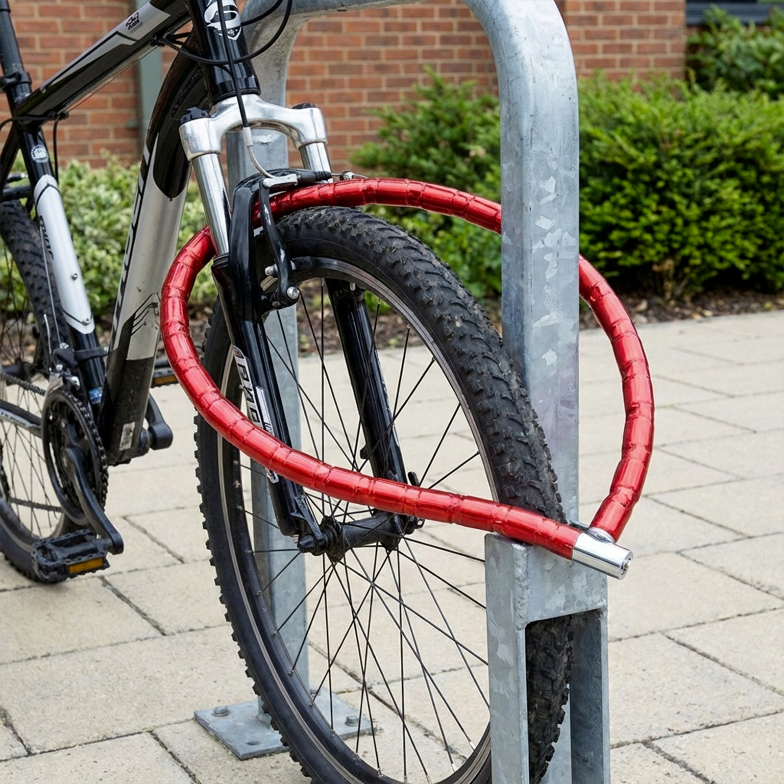 Ein schwarzes Fahrrad mit rotem Schloss, das an einem Metallständer befestigt ist.