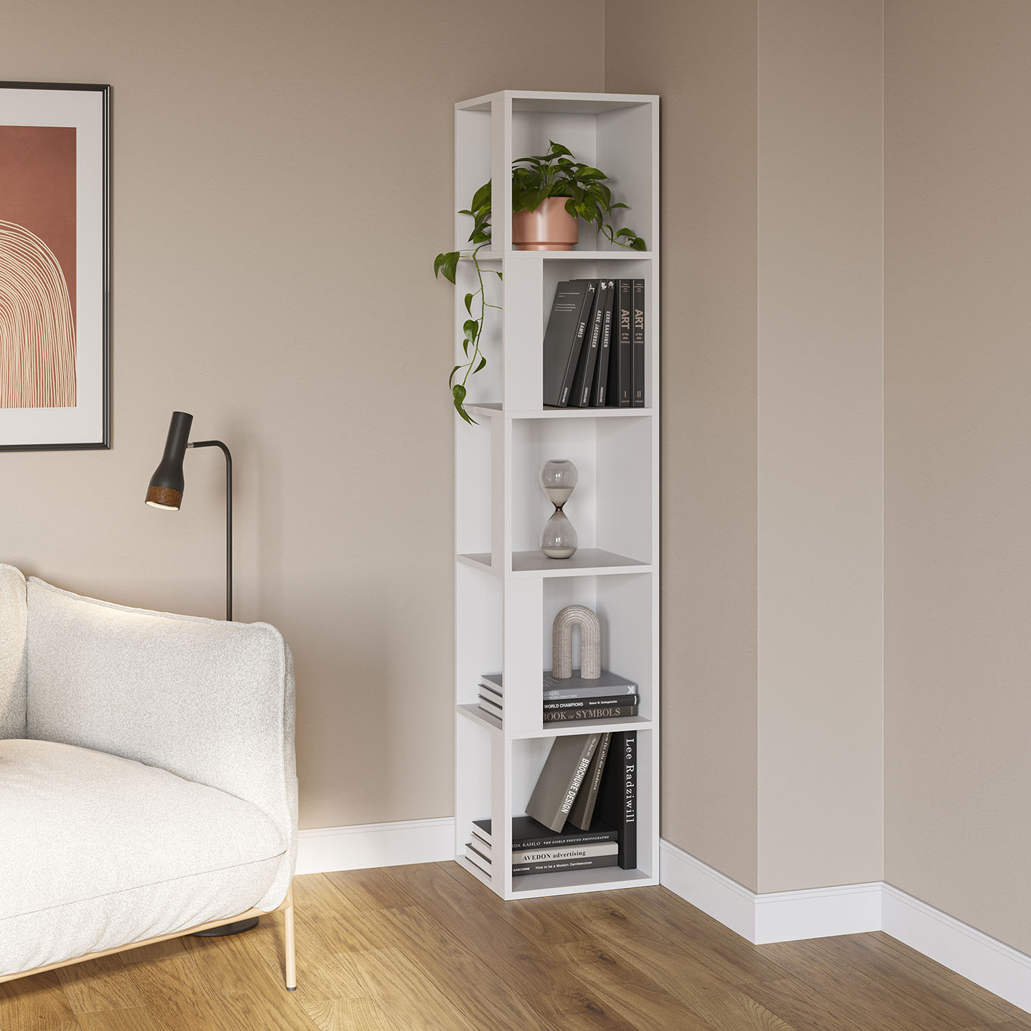 Una estantería blanca con libros, una planta y objetos decorativos junto a un sofá.