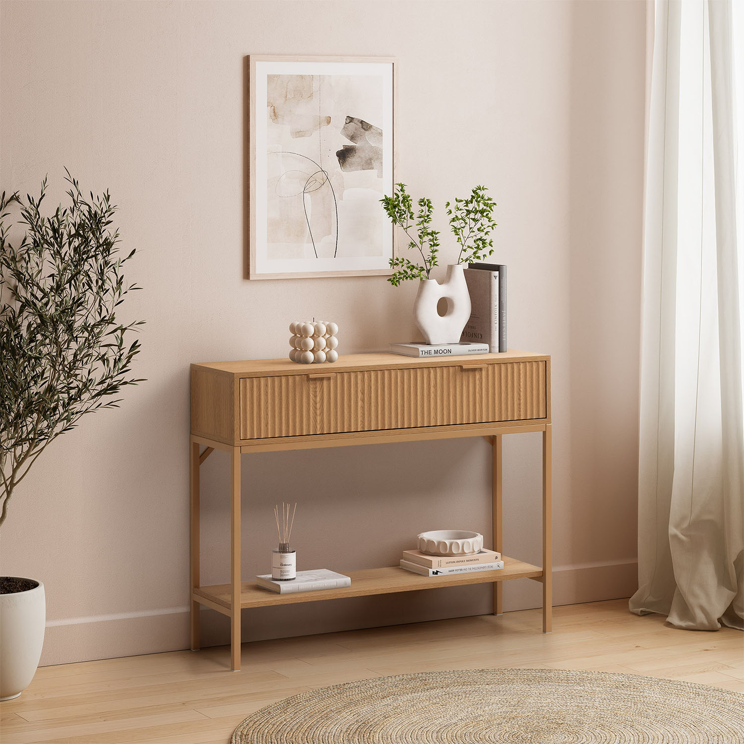 Una mesa consola de madera con cajón y estante, decorada con vela, jarrón, libros y planta.