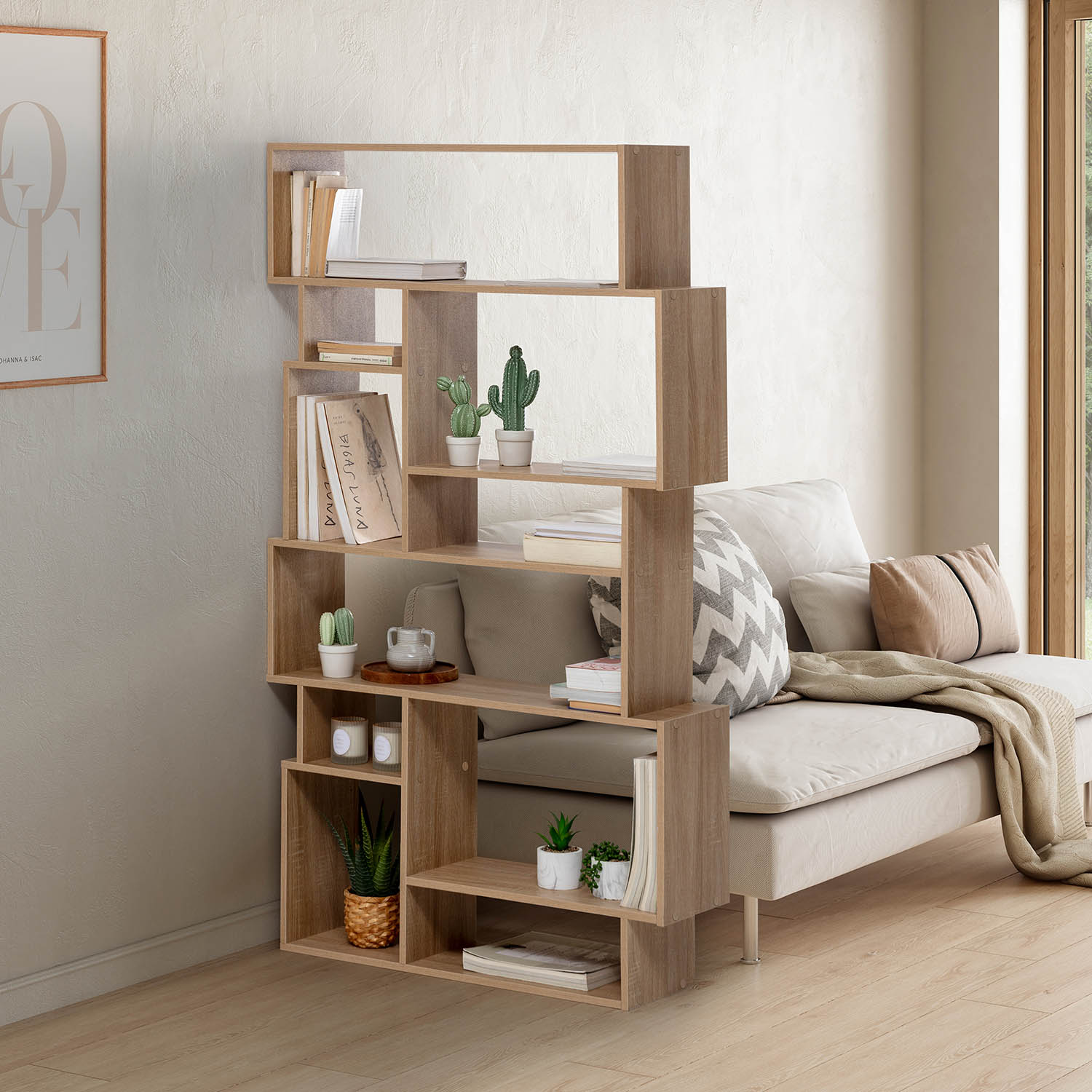 Una estantería de madera con libros, plantas y velas junto a un sofá.