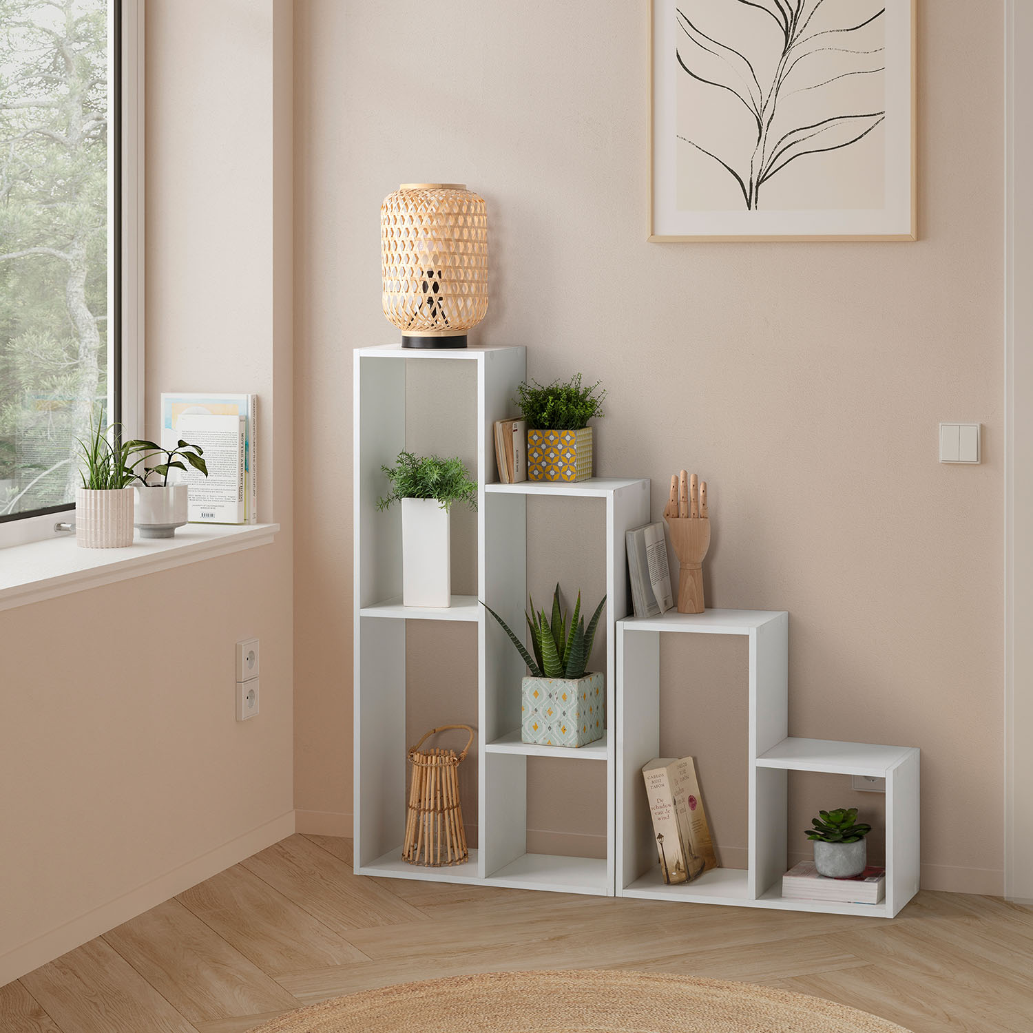 Un estante blanco con plantas, libros y decoración junto a una ventana.