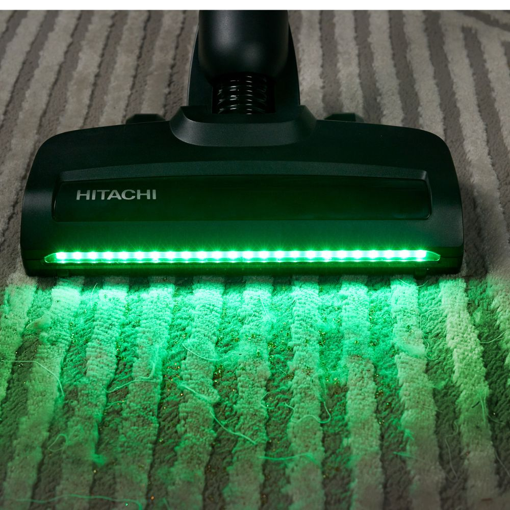 Ein Hitachi Staubsaugerkopf mit grünen Lichtern auf einem gestreiften Teppich.