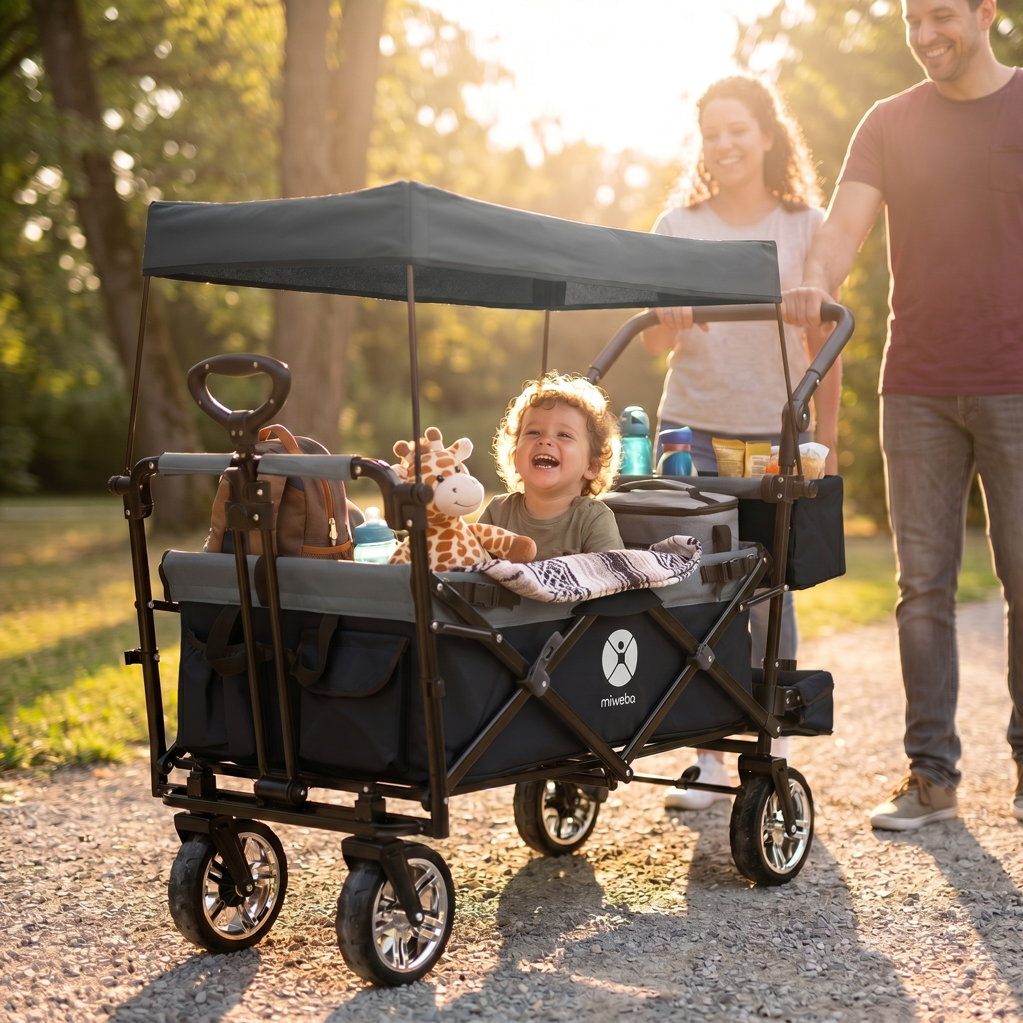 Ein lächelndes Kind sitzt in einem Wagen, den Eltern schieben. Sonnenuntergang im Park.