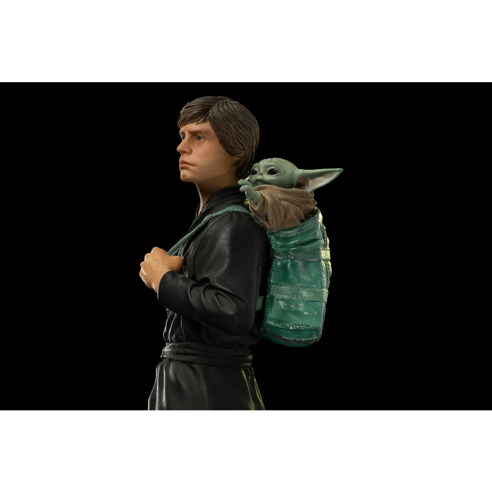 Luke Skywalker mit Baby Yoda auf dem Rücken in einer grünen Tasche.