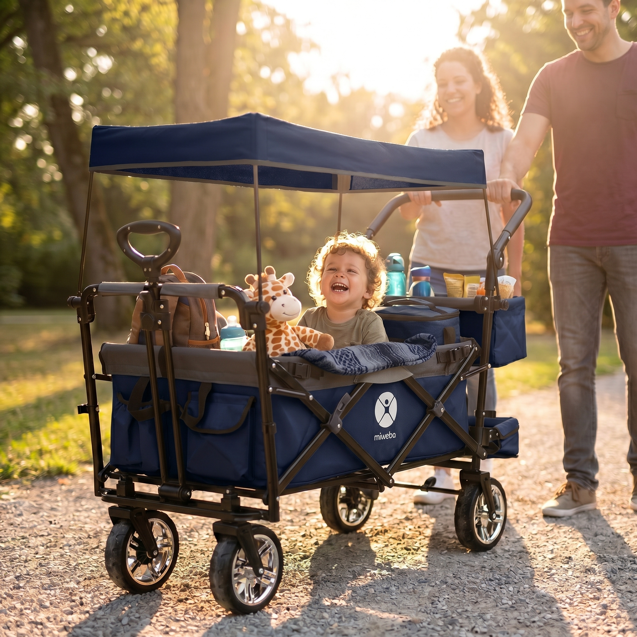 Ein lächelnder Junge sitzt in einem blauen Kinderwagen mit einem Giraffenspielzeug.