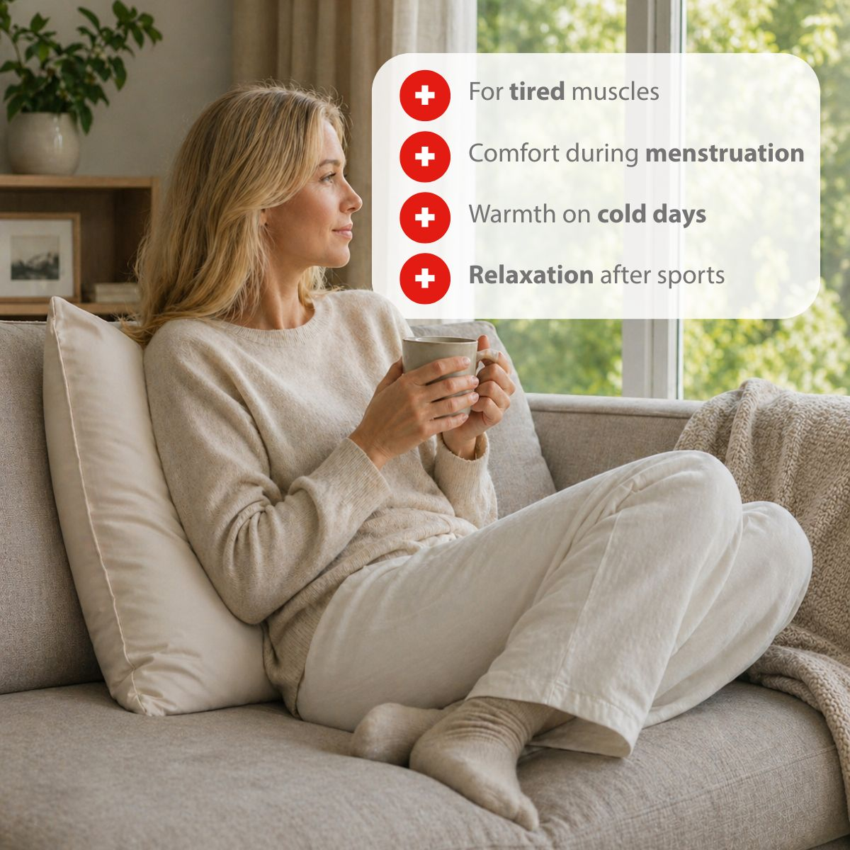A woman sits on a couch holding a mug.