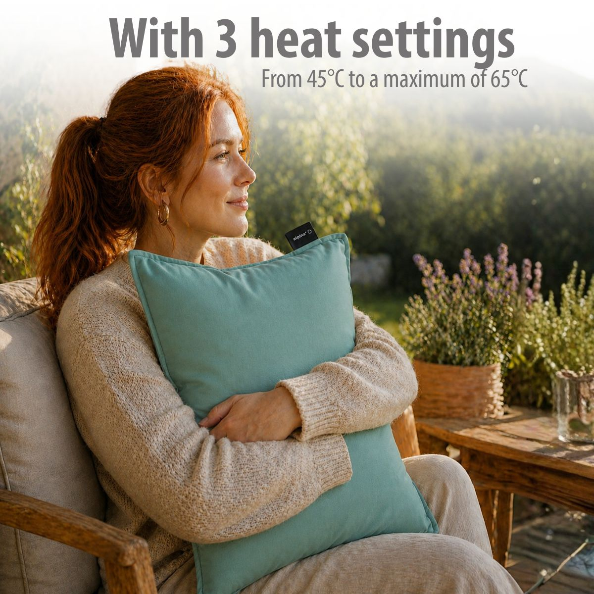 A woman with red hair holds a teal pillow outdoors.
