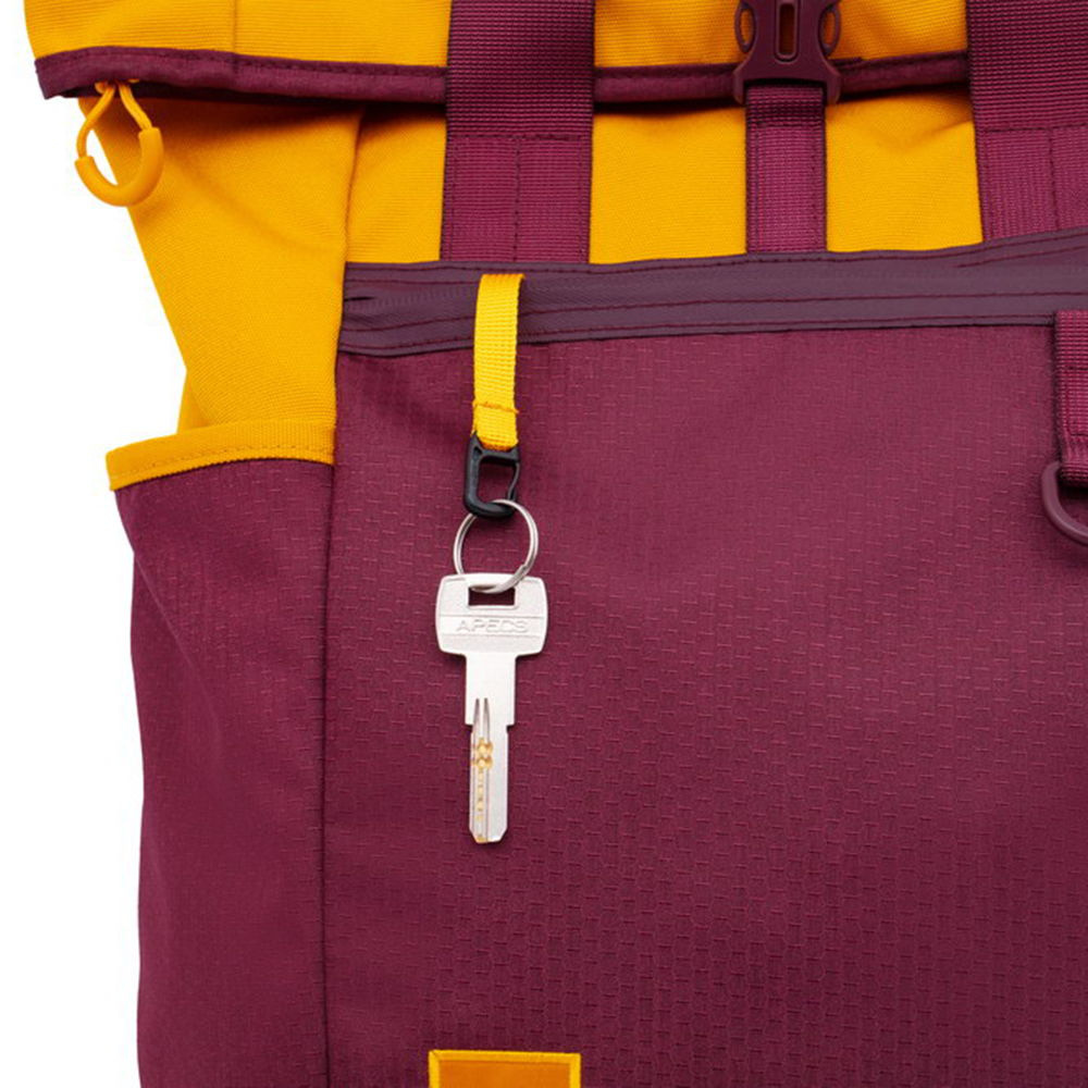 Una chiave pende da un cinturino giallo su uno zaino bordeaux.