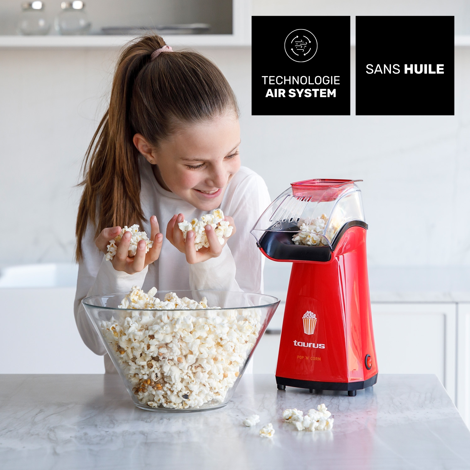 Una niña sostiene palomitas, junto a una máquina de palomitas roja y un bol.