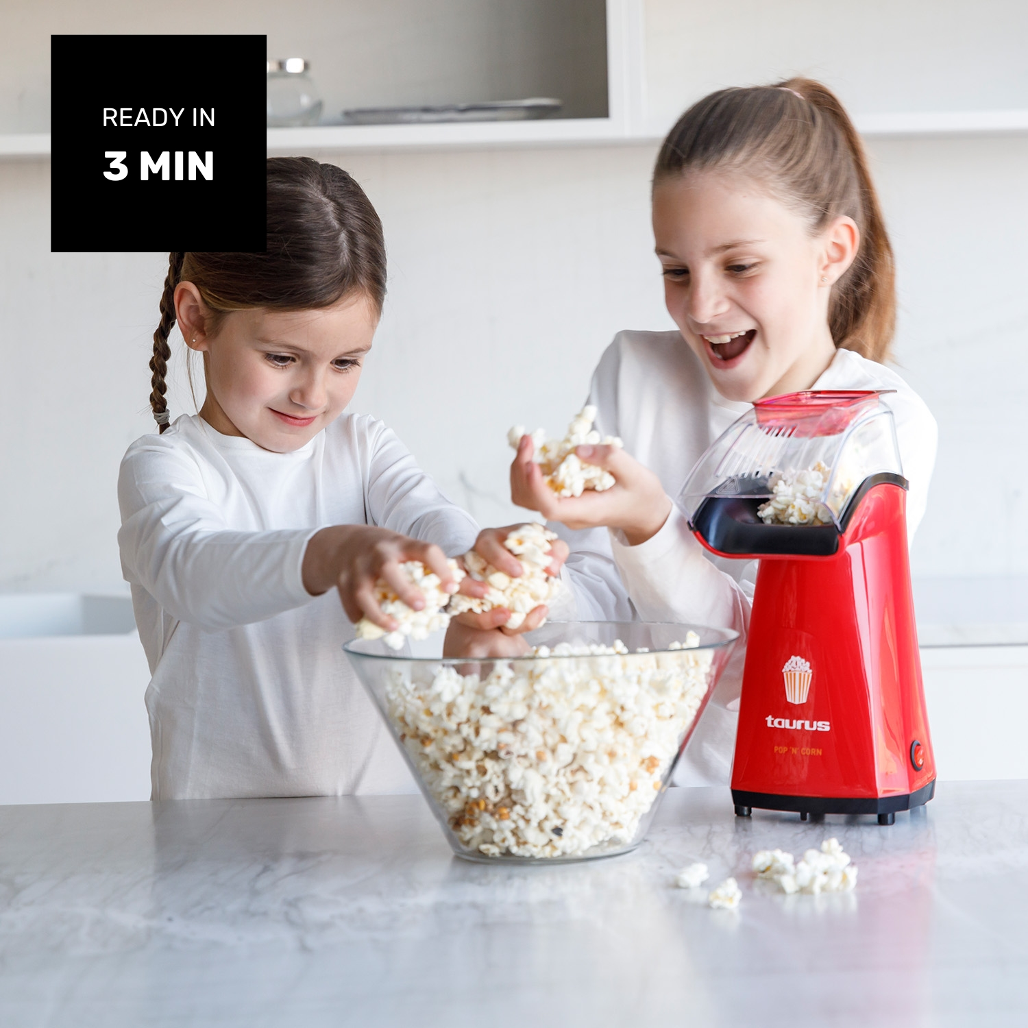Dos niñas haciendo palomitas con una máquina roja. Listo en 3 minutos.