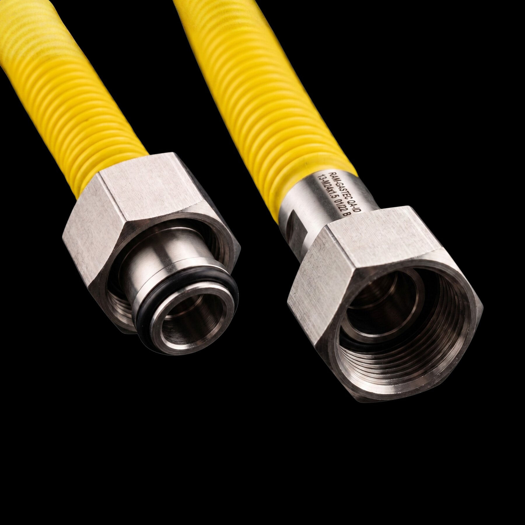 Two yellow gas hoses with metal fittings on a black background.