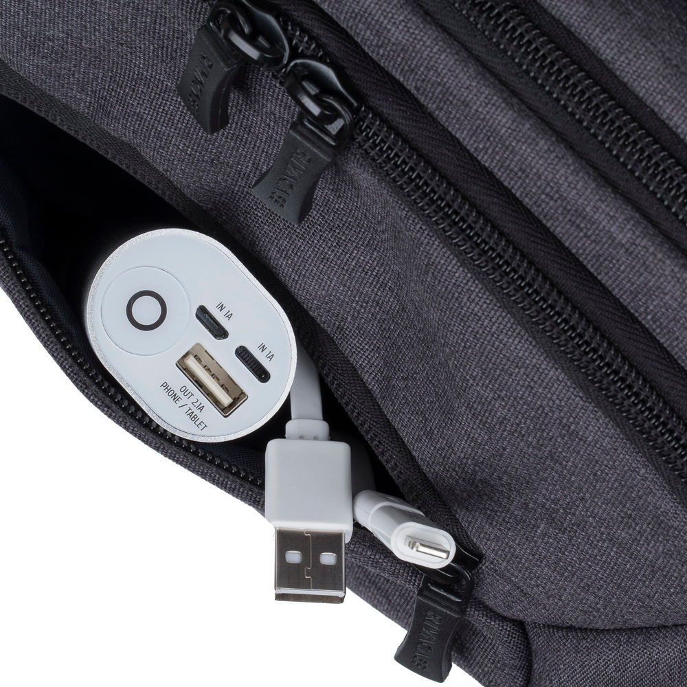 Srebrny power bank i białe kable USB znajdują się w kieszeni ciemnoszarej torby.