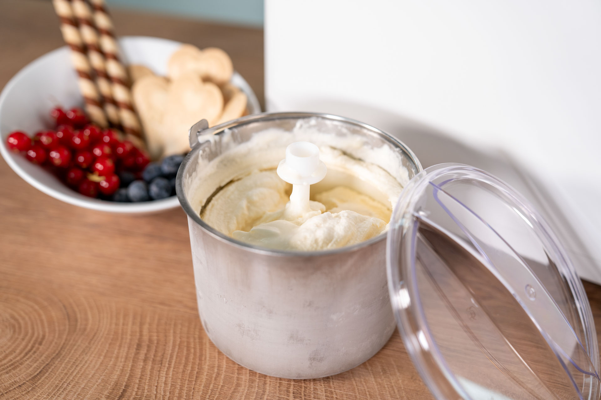Eiscreme im Gefrierbehälter neben Beeren und Keksen.