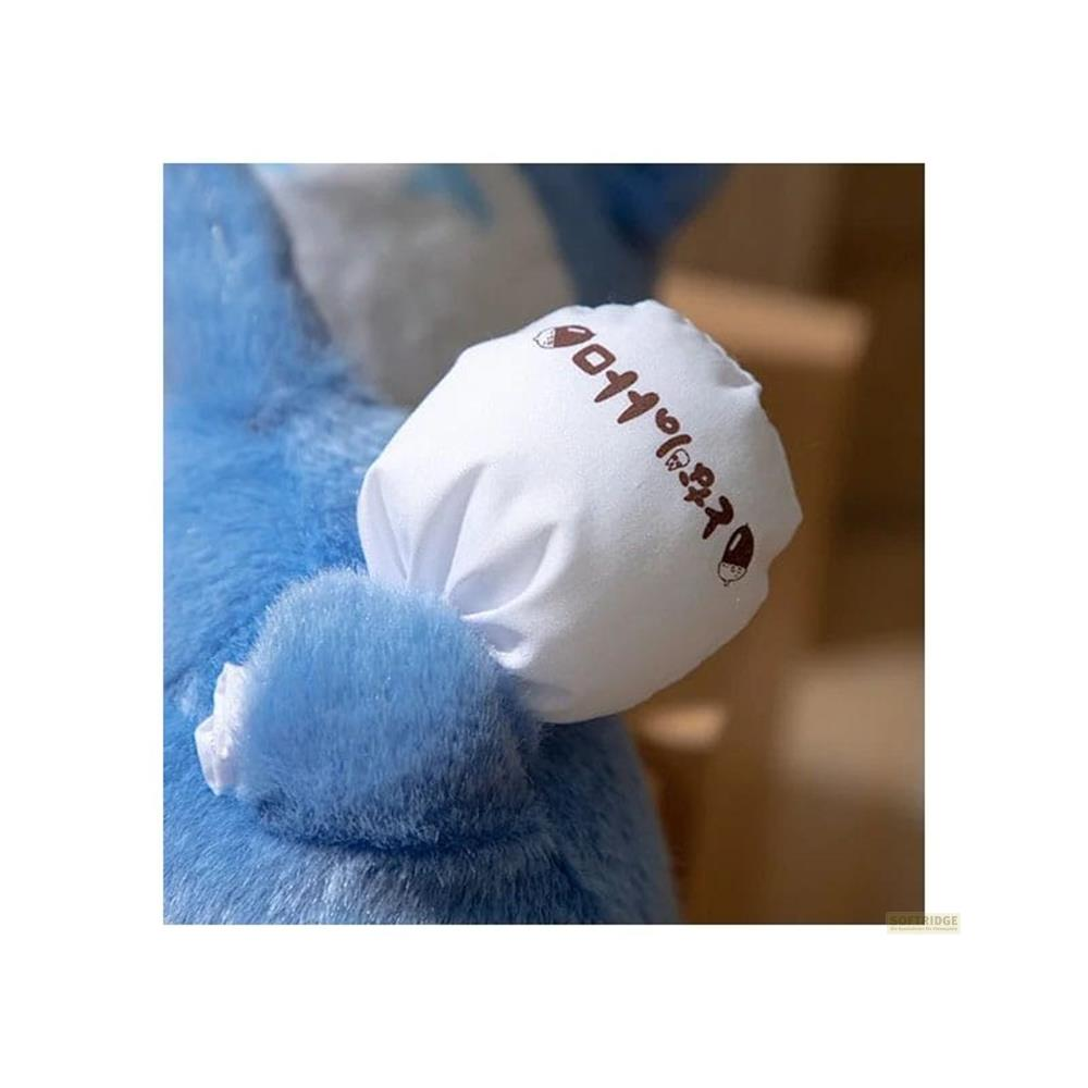 Eine blaue Plüschfigur mit einem weißen Stoffärmel, der mit brauner Schrift verziert ist.