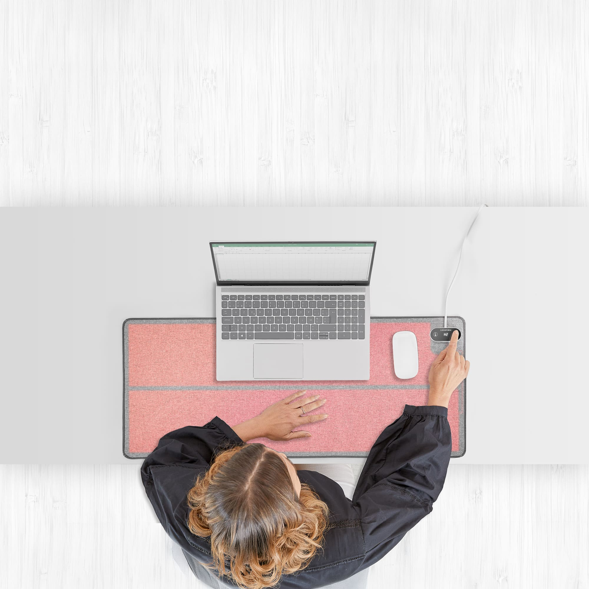 Bovenafbeelding van een persoon die een laptop gebruikt, muis op roze mat.