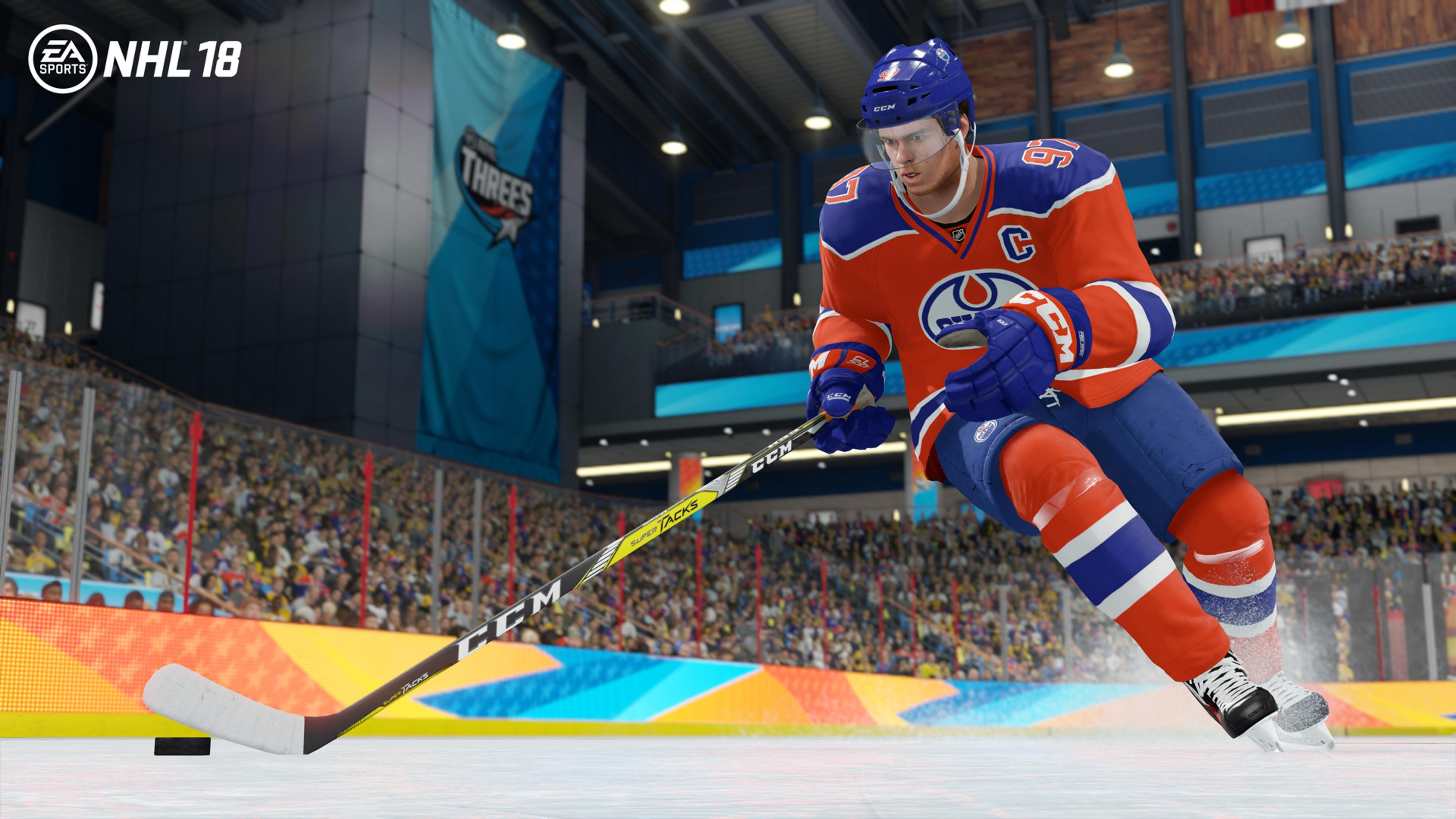 Eishockeyspieler in Orange und Blau auf Eis, Puck und Schläger sichtbar.