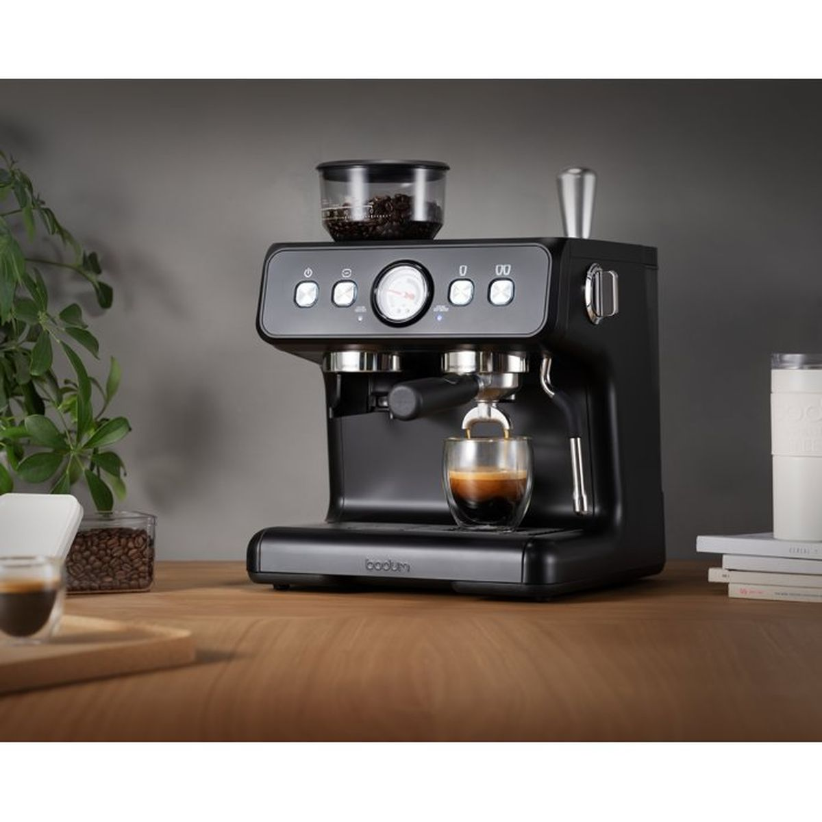 Una macchina per espresso nera con chicchi di caffè e un bicchiere di espresso.