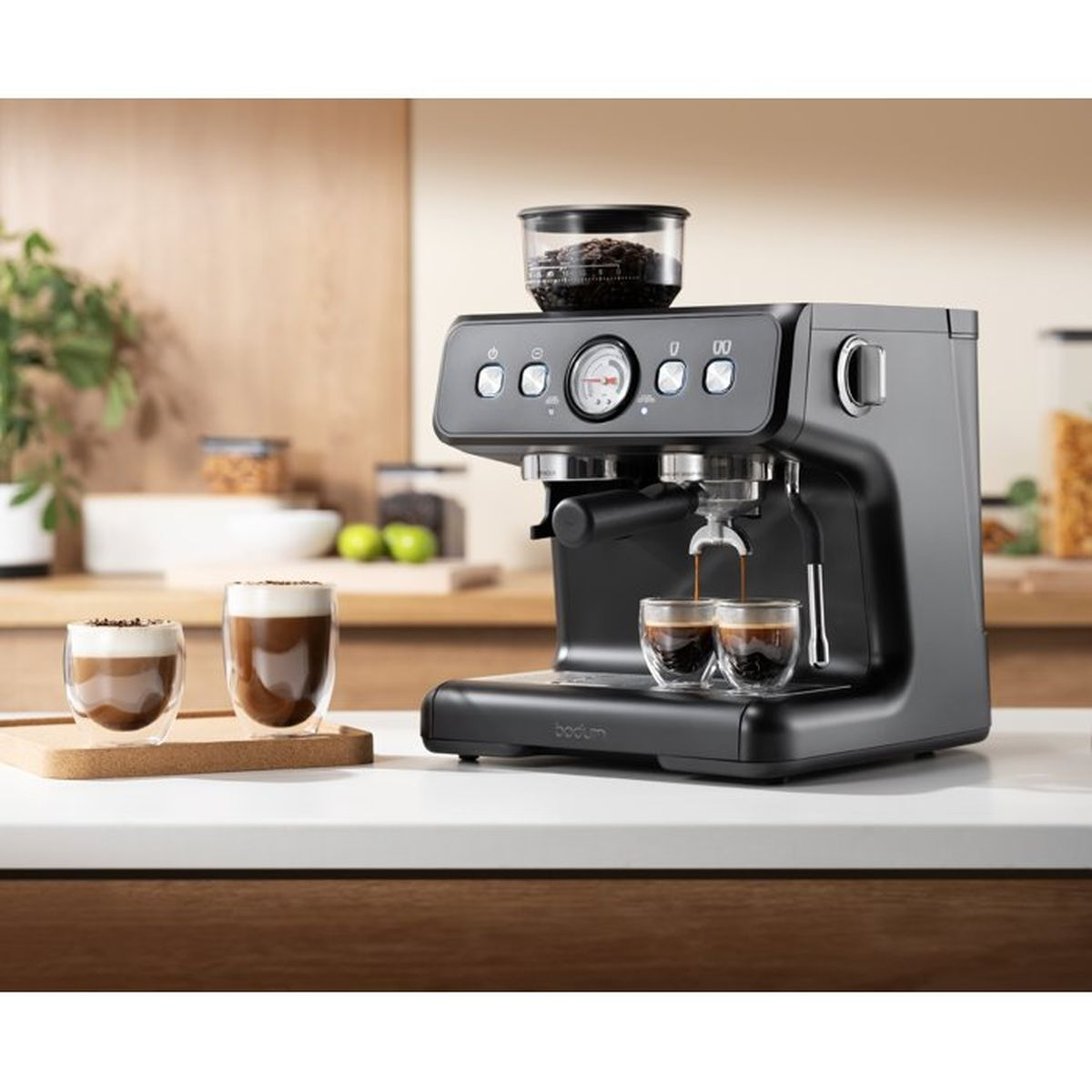Una macchina per espresso nera prepara caffè in due bicchieri su un piano di lavoro.