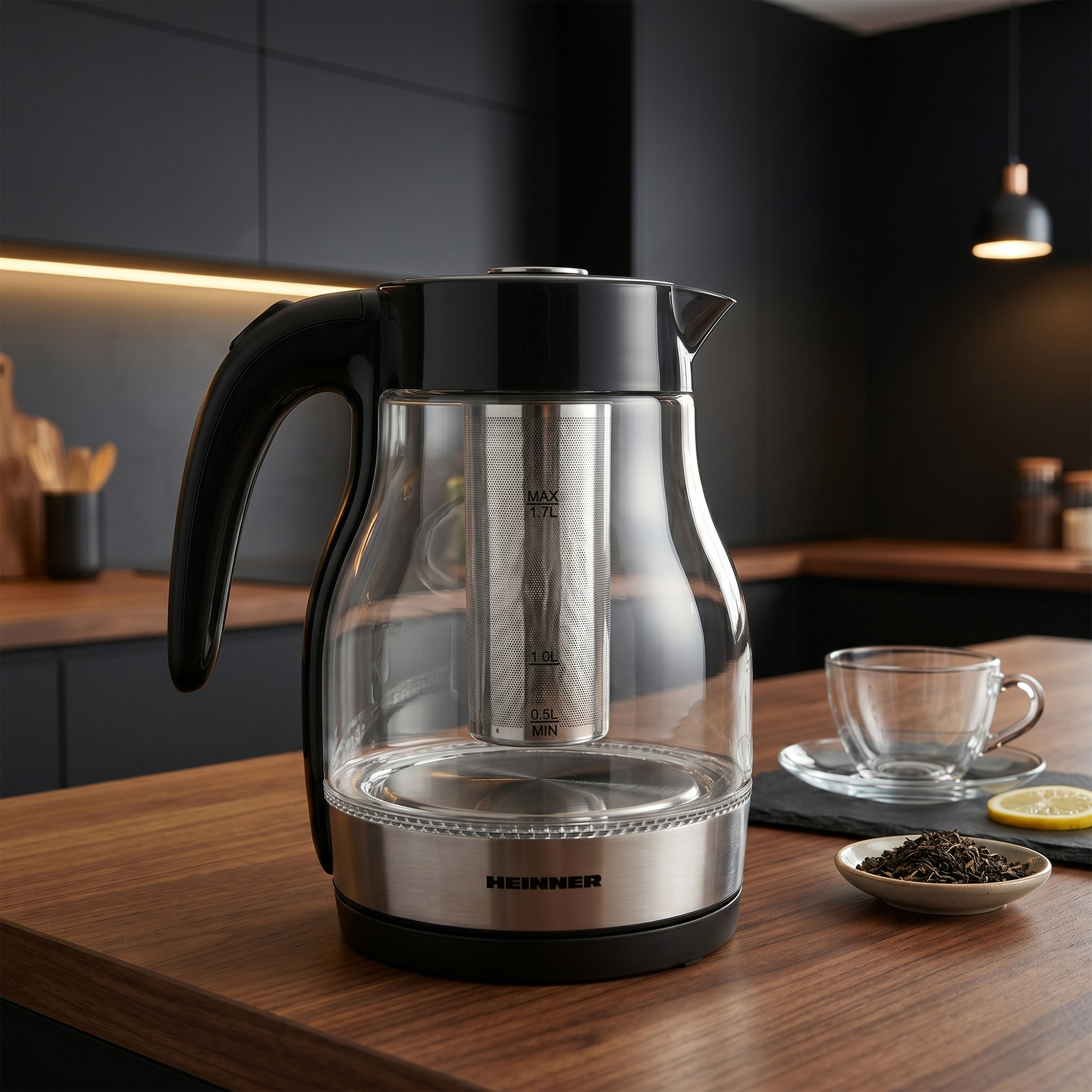 Een glazen waterkoker met zwarte handgreep en metalen deksel staat op een houten tafel.