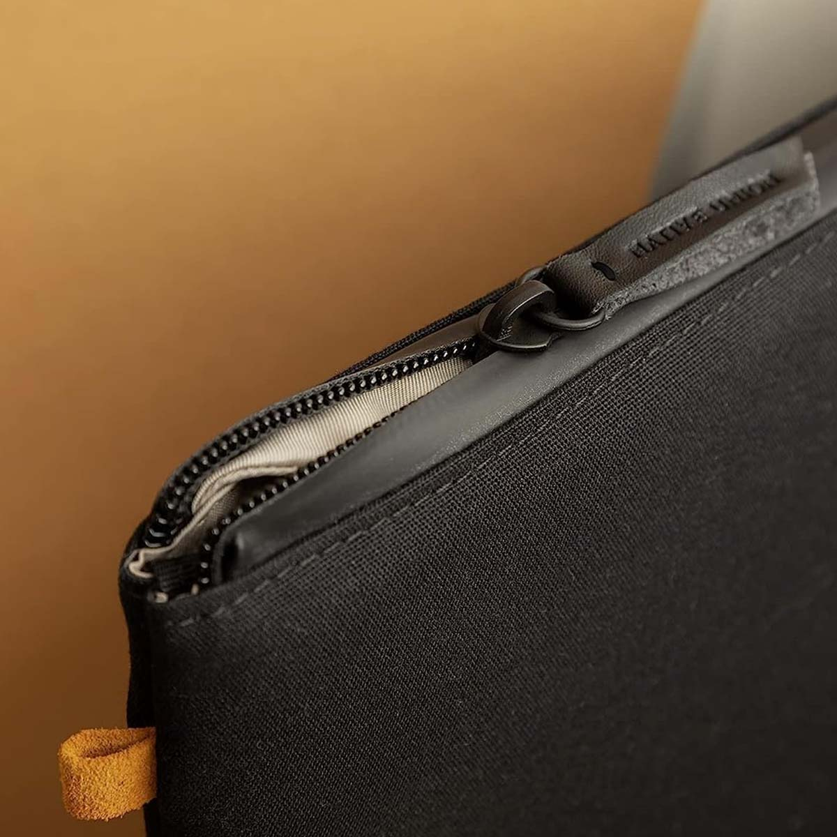 Primo piano di una borsa nera con cerniera ed etichetta in pelle.