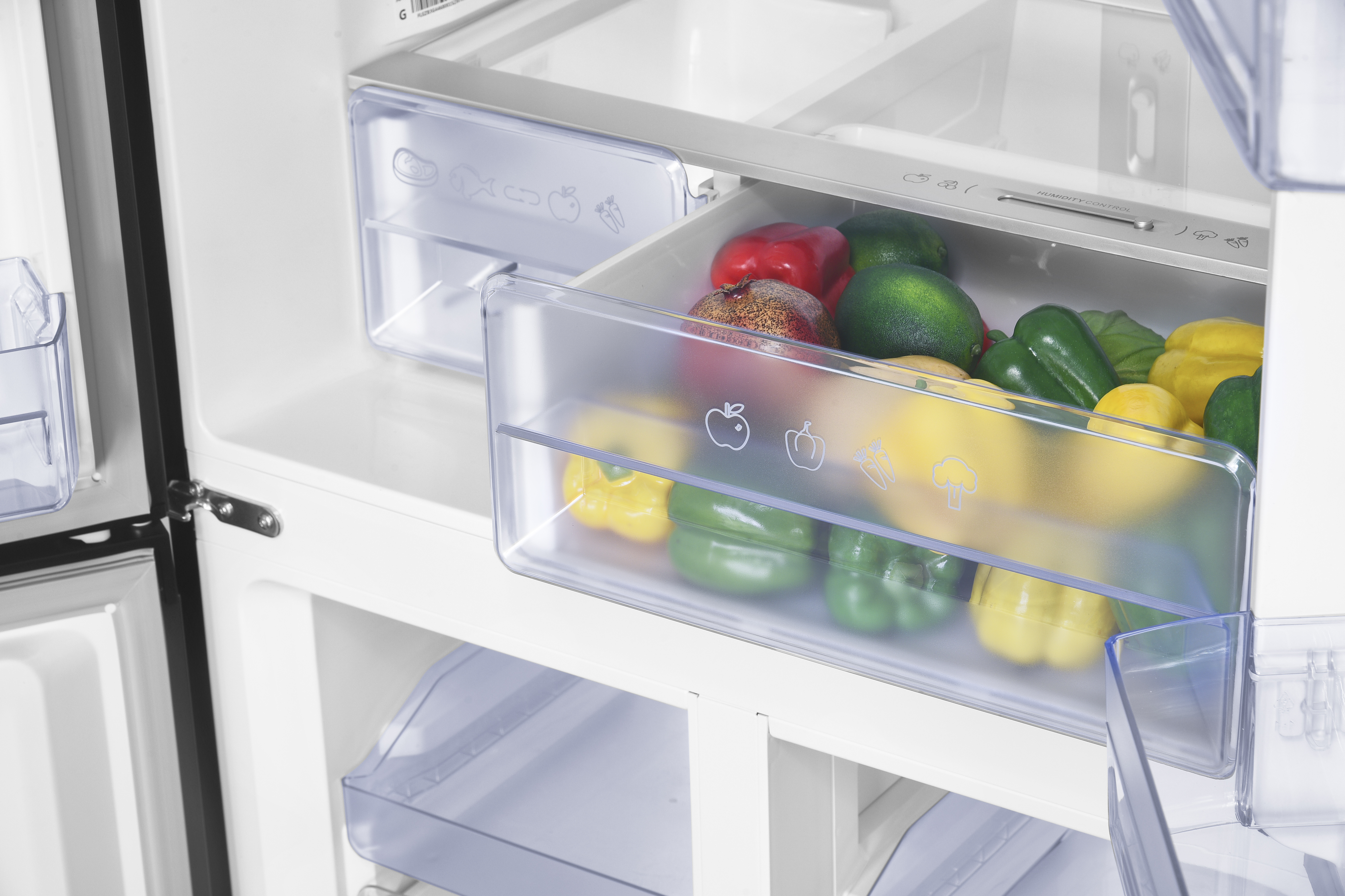A refrigerator drawer filled with colorful bell peppers, lemons, and pomegranates.