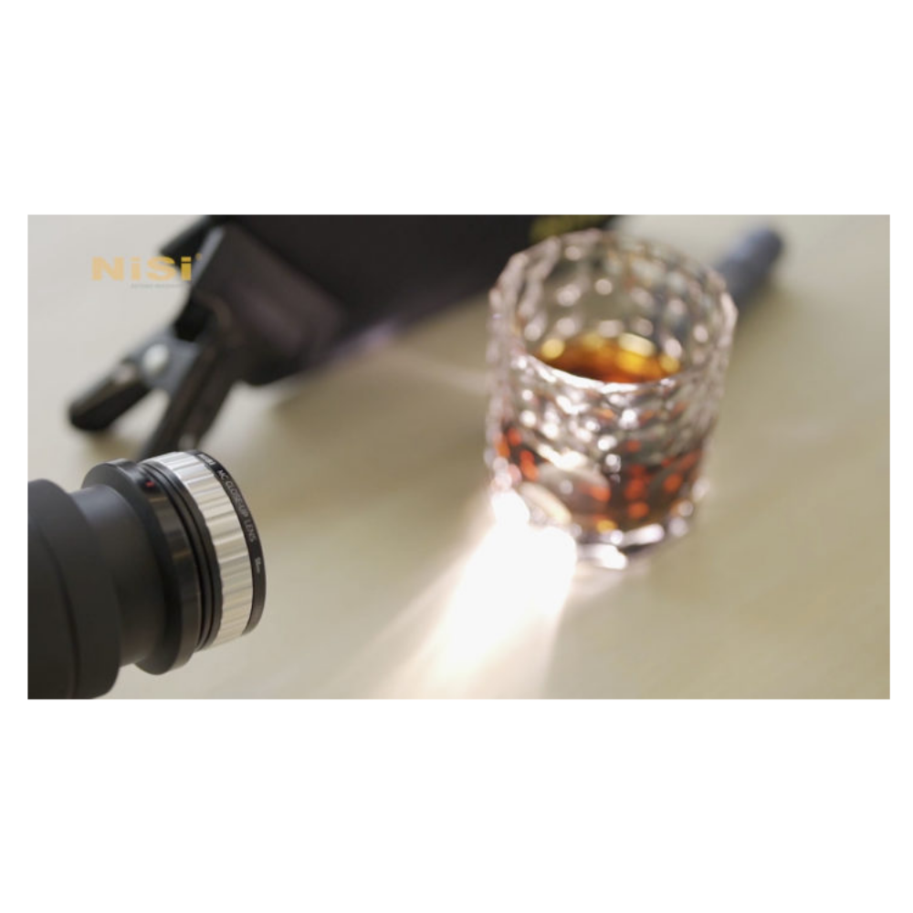 Een glas whisky naast een camera met Nisi-logo.