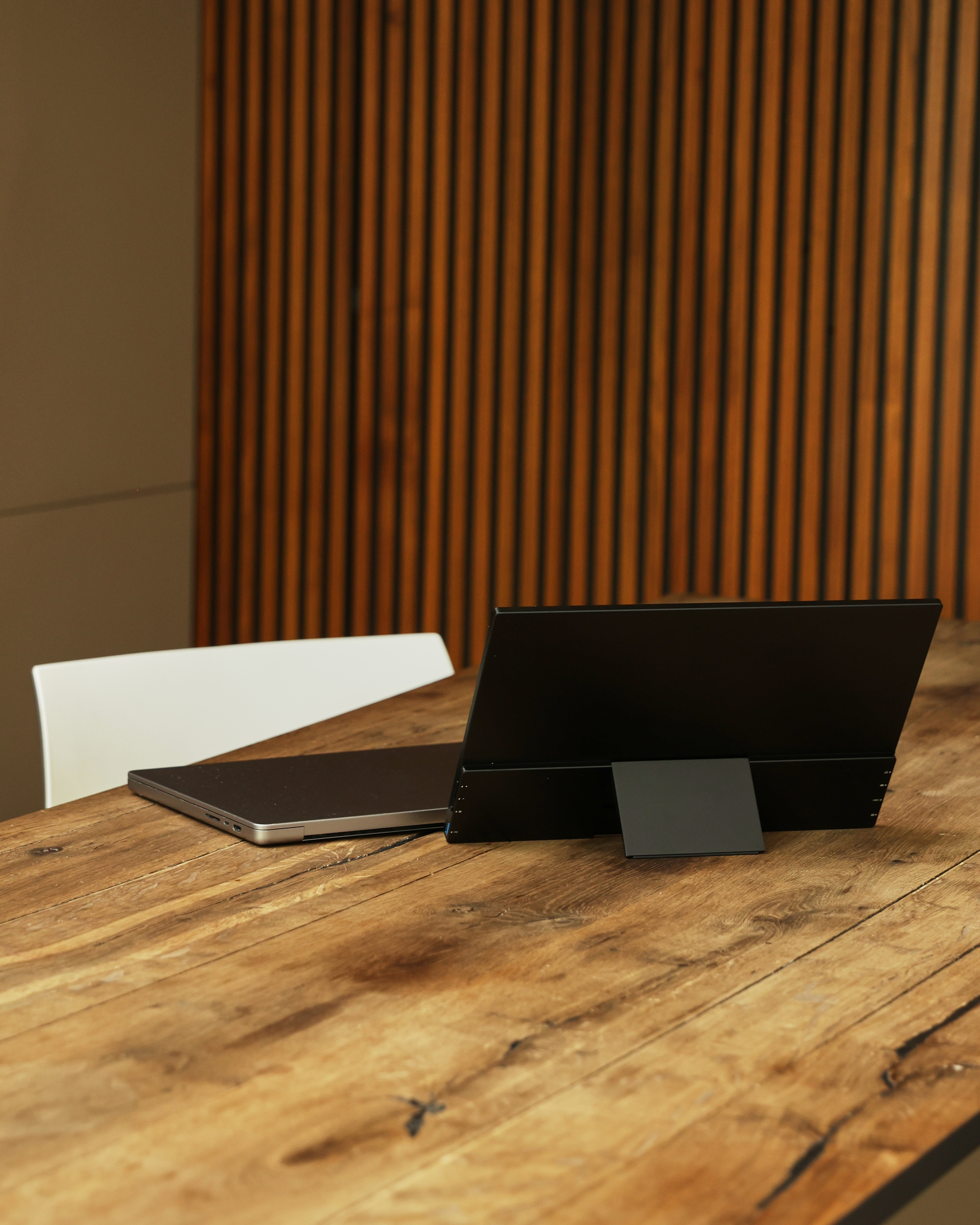 Un ordinateur portable noir et un moniteur sur une table en bois.