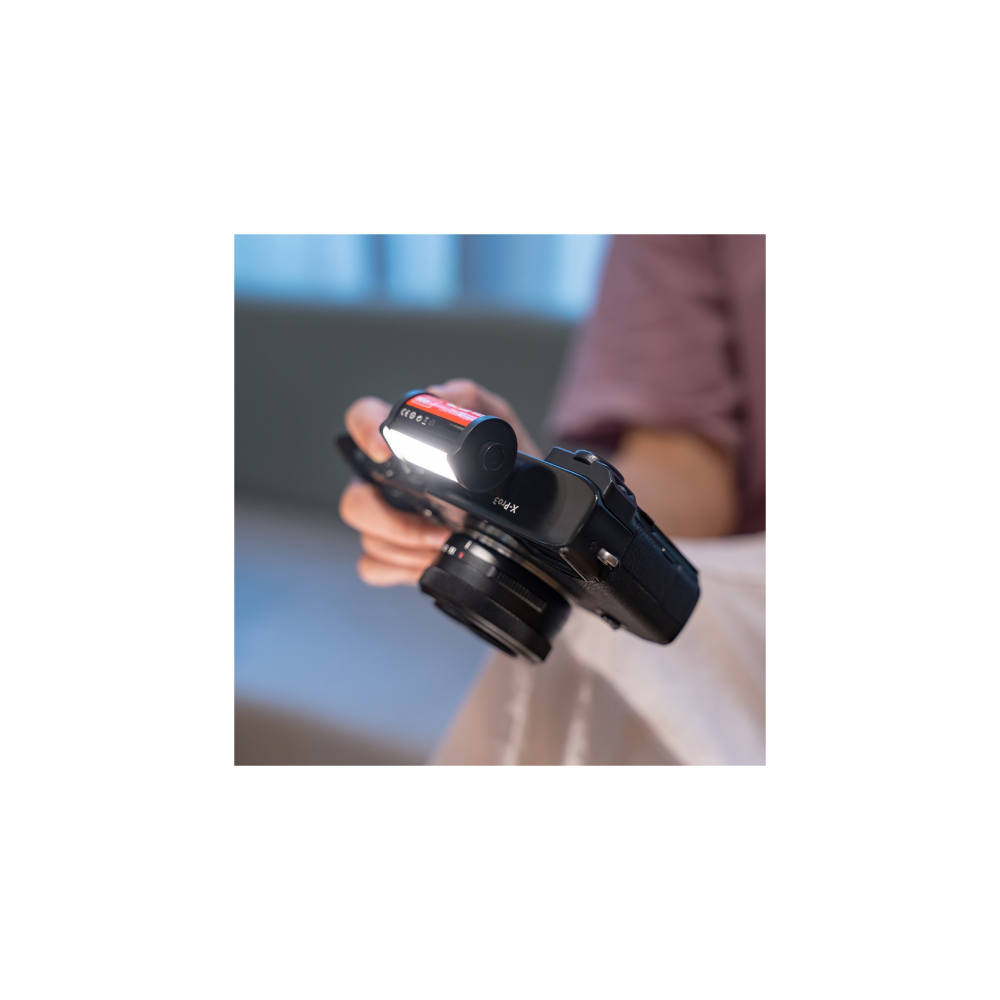 Een hand houdt een camera vast met een helder LED-lampje vooraan.