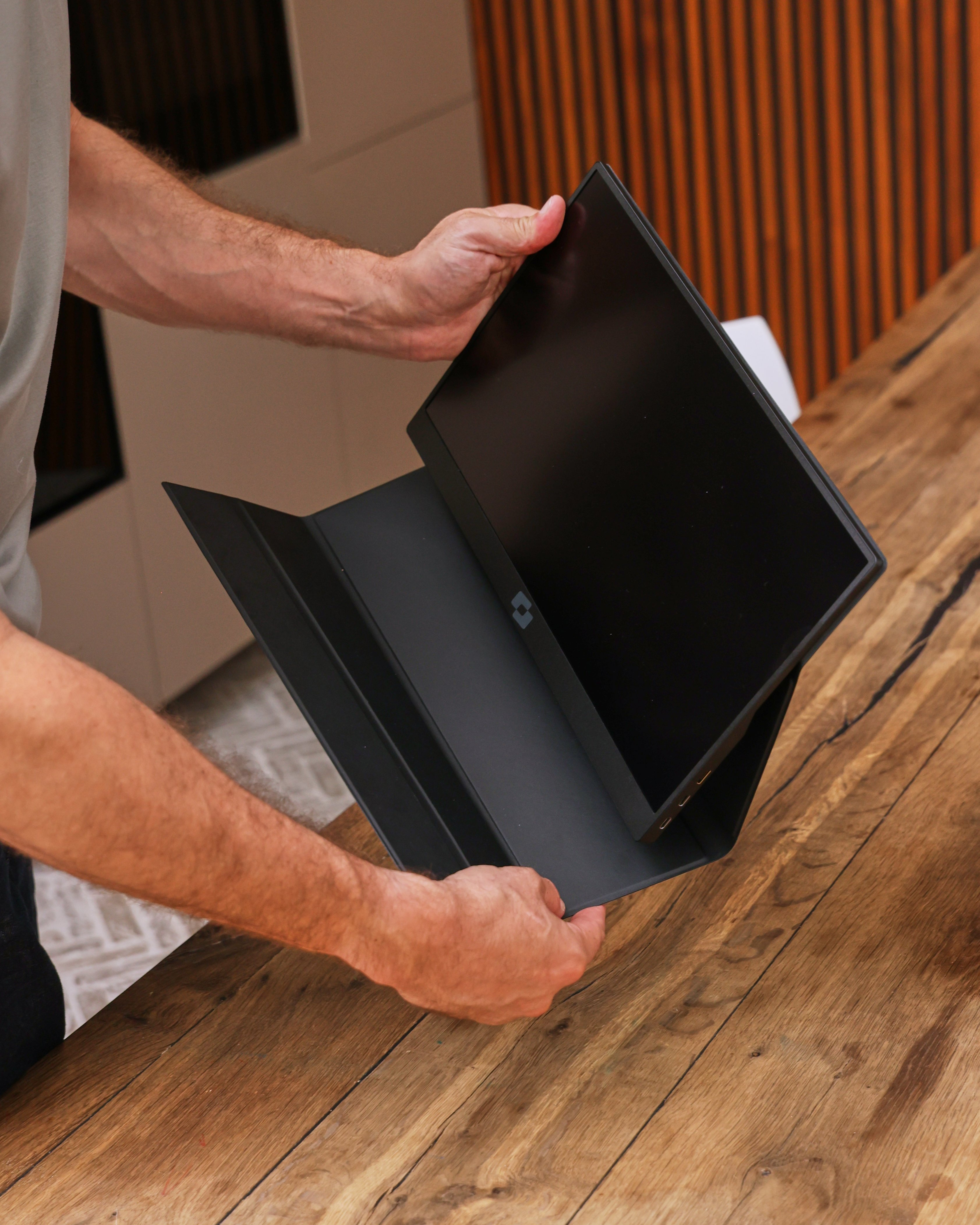 A person holds a black monitor in a black protective case.