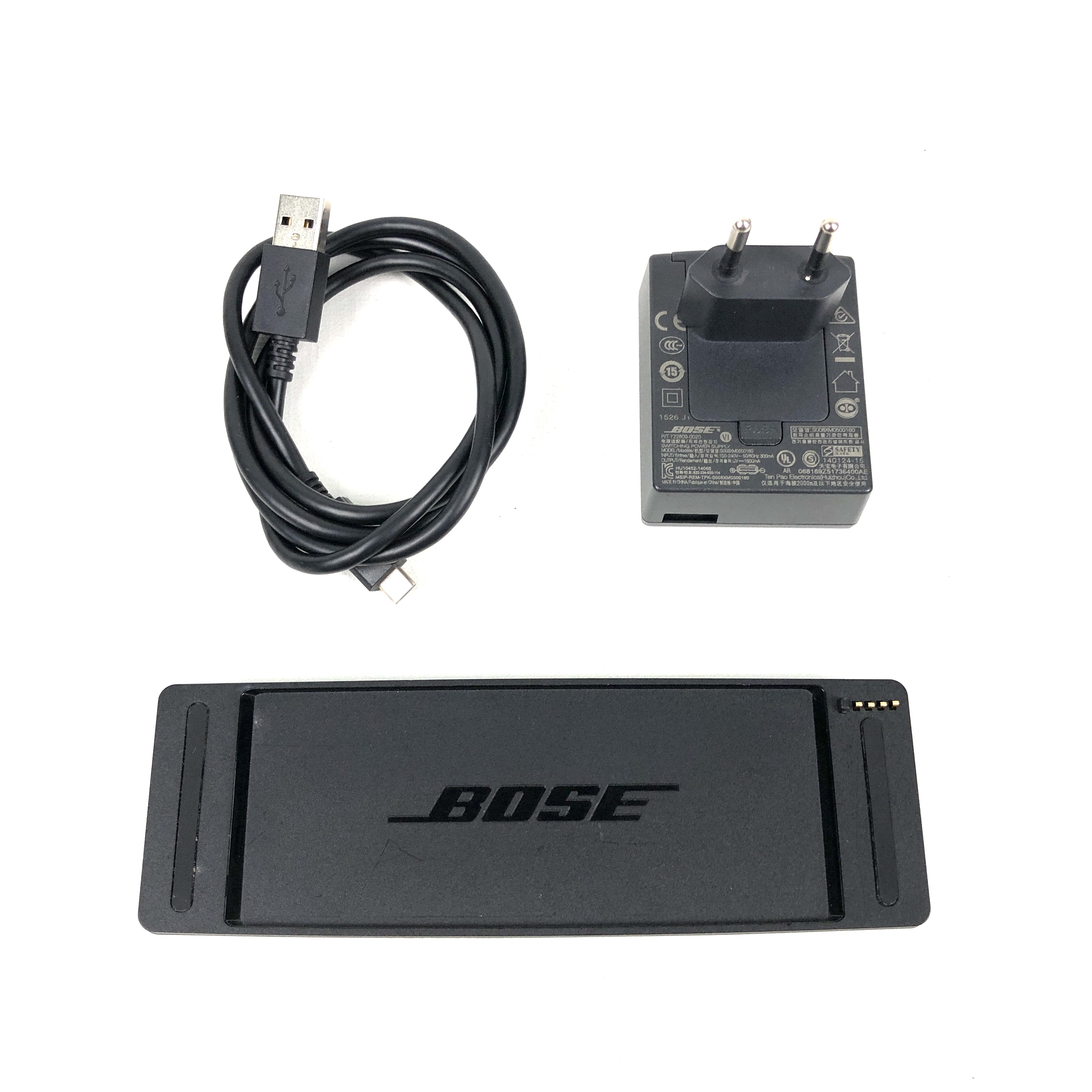 Schwarzes Bose Ladekabel, Netzteil und Ladezubehör auf weißem Hintergrund.