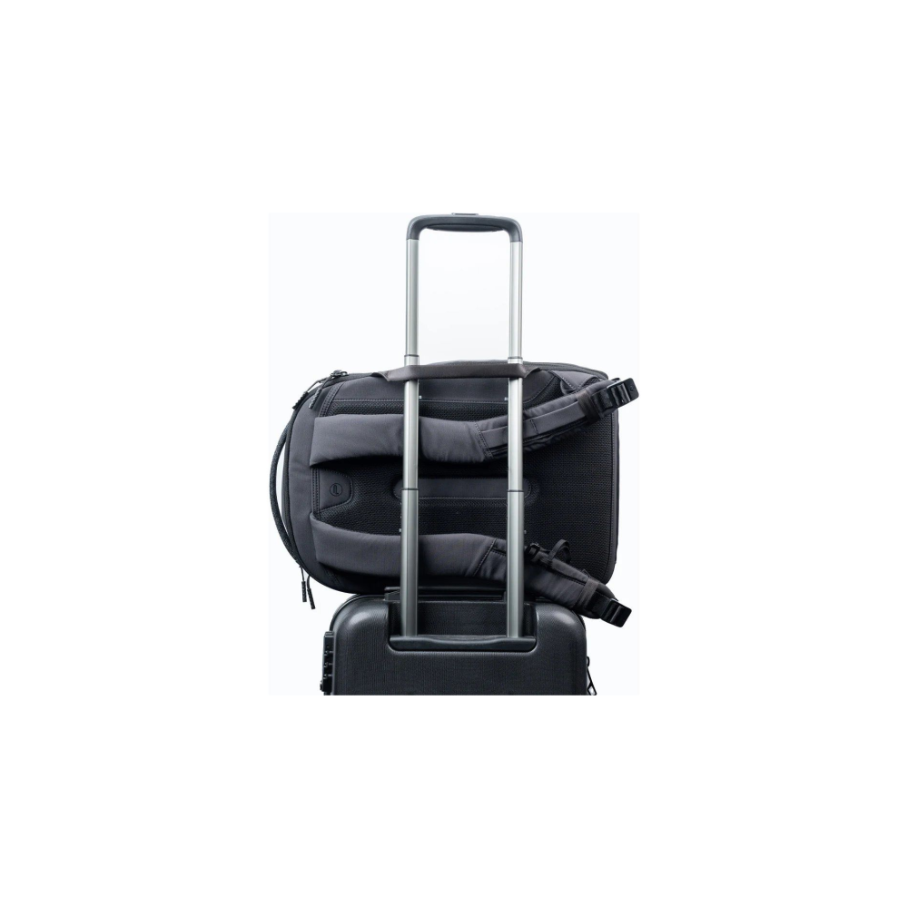 A black backpack rests on a black suitcase with a silver telescoping handle.
